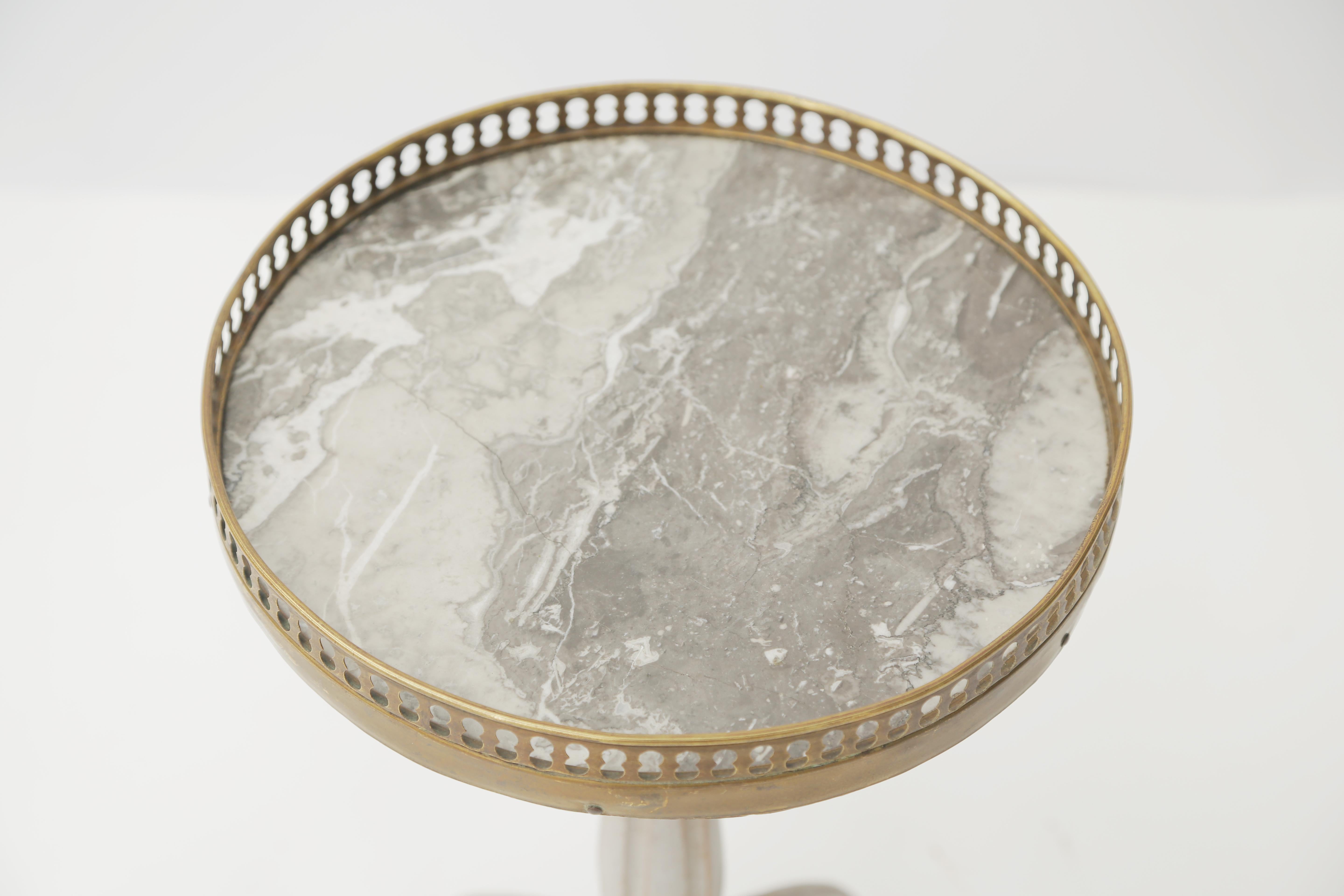Petite bouillotte accent table, having a round top of bardiglio gray marble, surrounded by a pierced gallery of brass, raised on a painted, fluted, balustrade-form pedestal base, to its splayed legs.

Stock ID: D3130