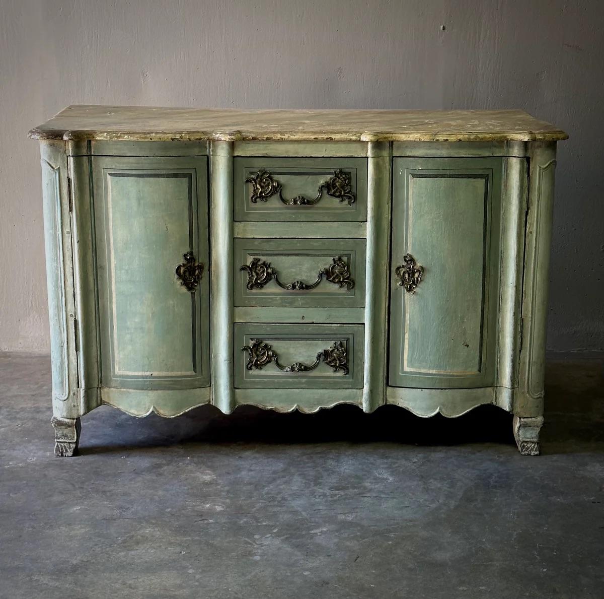 Mobile buffet o credenza neoclassico della metà del XVIII secolo proveniente dalla Normandia. Dipinto in una serena tonalità di celadon con un piano in finto marmo, questo pezzo presenta un grembiule intagliato, piedi a staffa e ferramenta dorata.