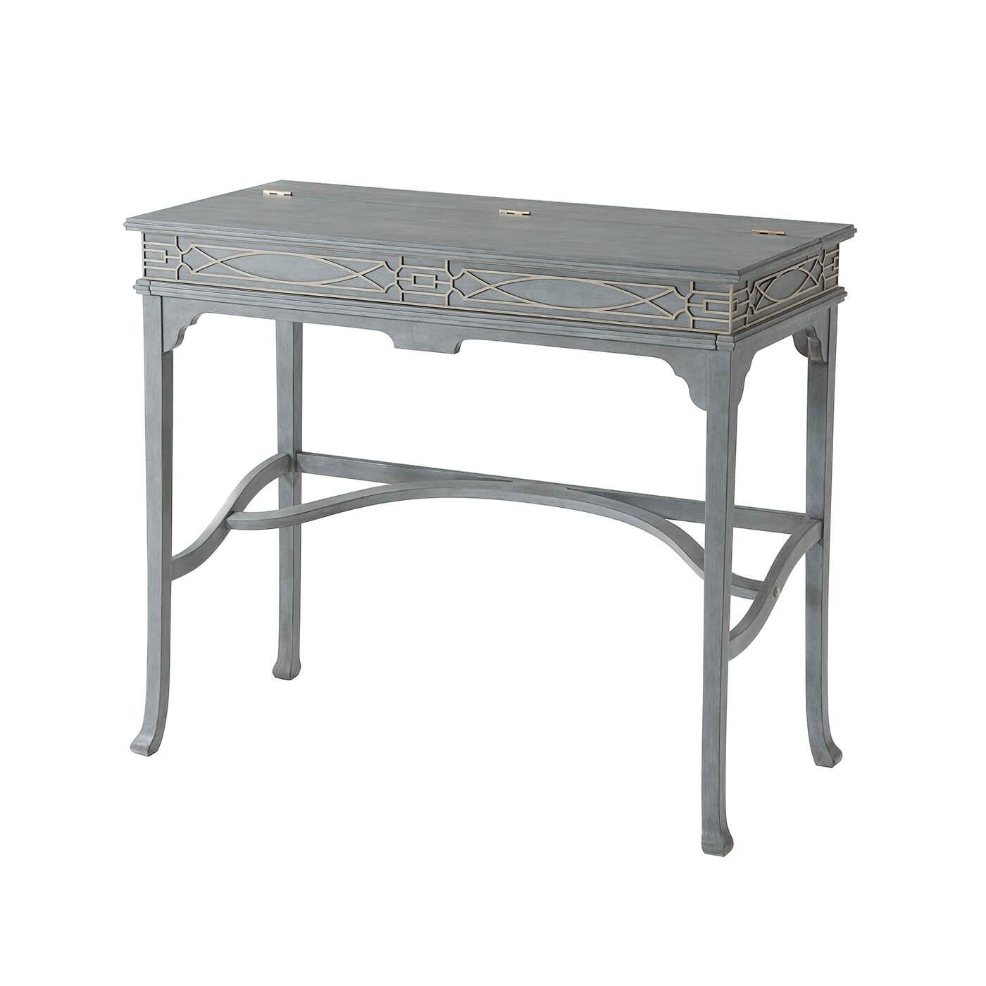 A vintage greyed limestone painted campaign desk, with a Chinese Chippendale blind fret decorated frieze, the hinged top opening to reveal a blue leather writing surface and pigeonholes, on splayed legs joined by stretchers.

Dimensions: 40