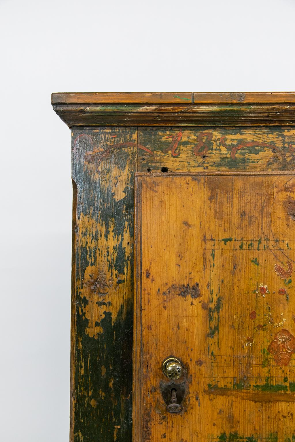 Painted Central European food cupboard has the original working lock and key, original heavy steel hinges, and the original floral painting. There are exposed dovetails on the top and chamfered corners on the front. The base has a scalloped apron.