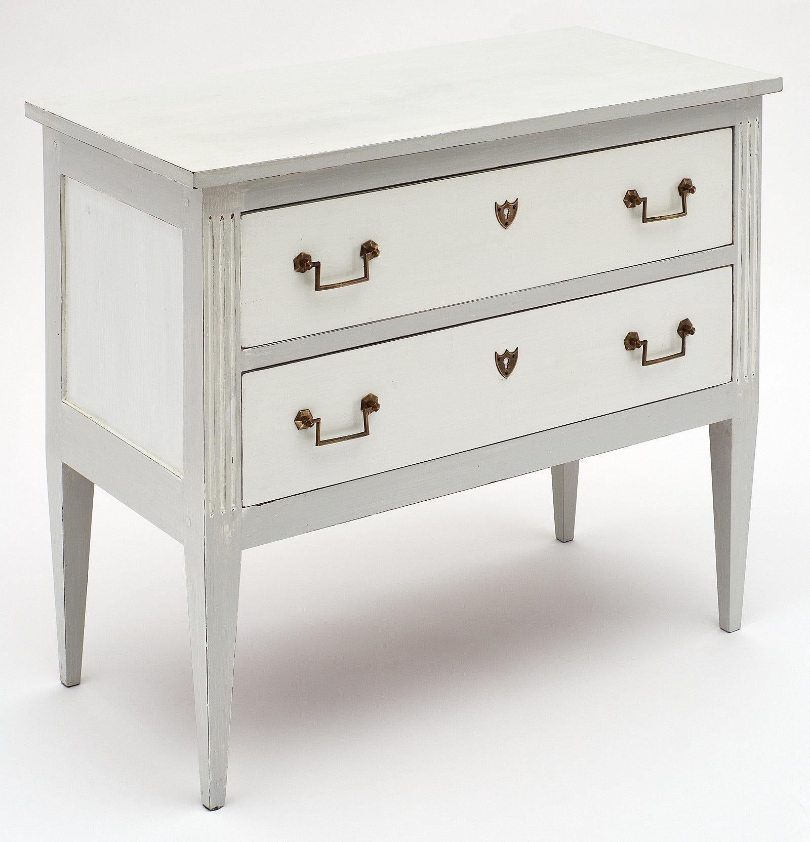 French antique Louis XVI style painted cherry chest of drawers “commode sauteuse” featuring a “Trianon” gray and white finish with patina. The brass hardware is all original. Two large dovetailed drawers offer ample storage. We love the classic