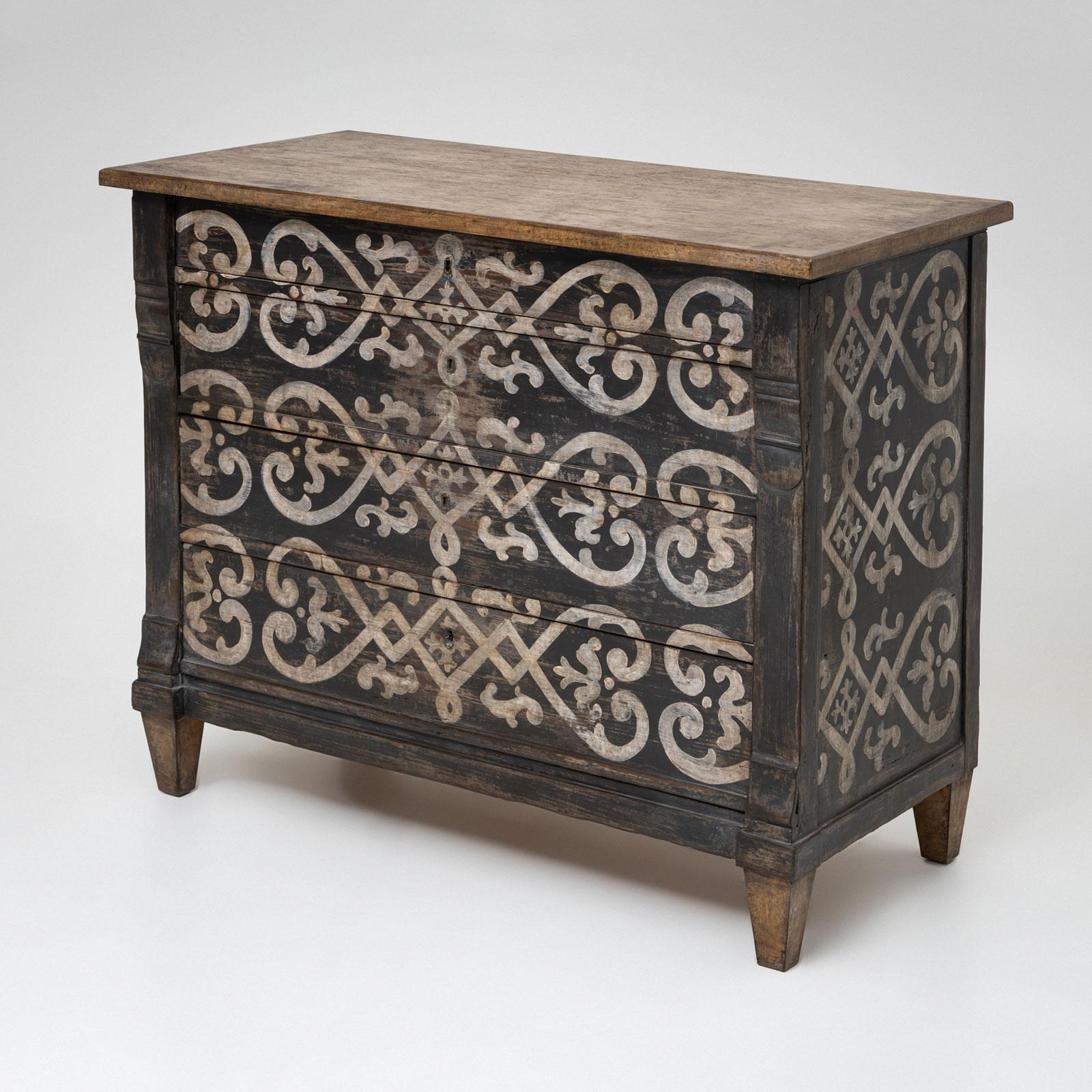A small pine dresser from the mid-19th century, featuring four drawers. The side pilasters are adorned with subtle volute motifs, adding a touch of classical elegance. The gray-and-white paint finish is antiqued with a patina and showcases a playful