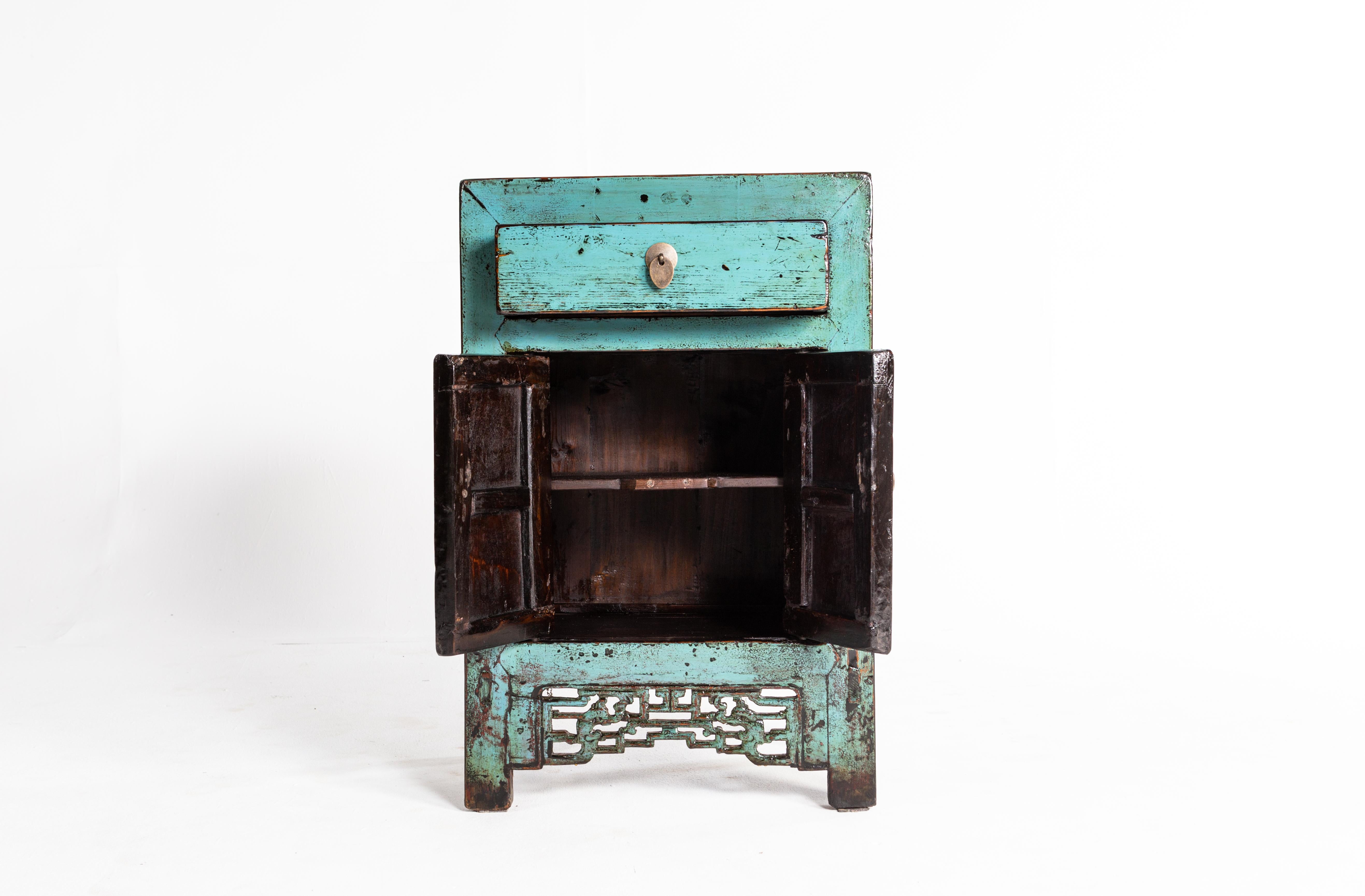 This cabinet is from Shanxi, China and was made from pine wood, circa 1920. The piece features a drawer, a pair of doors, green paint, and a shelf for storage. Wear consistent with age and use.