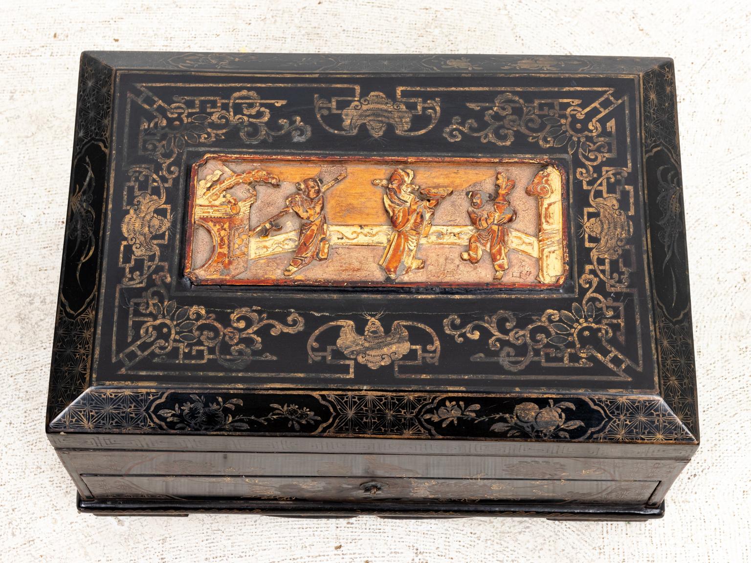Painted Chinese style box ornamented throughout with motifs such as flowers, birds, and Greek key trim. The piece also features a carved panel on the lid with three figures. Please note of wear consistent with age including paint loss, finish loss,