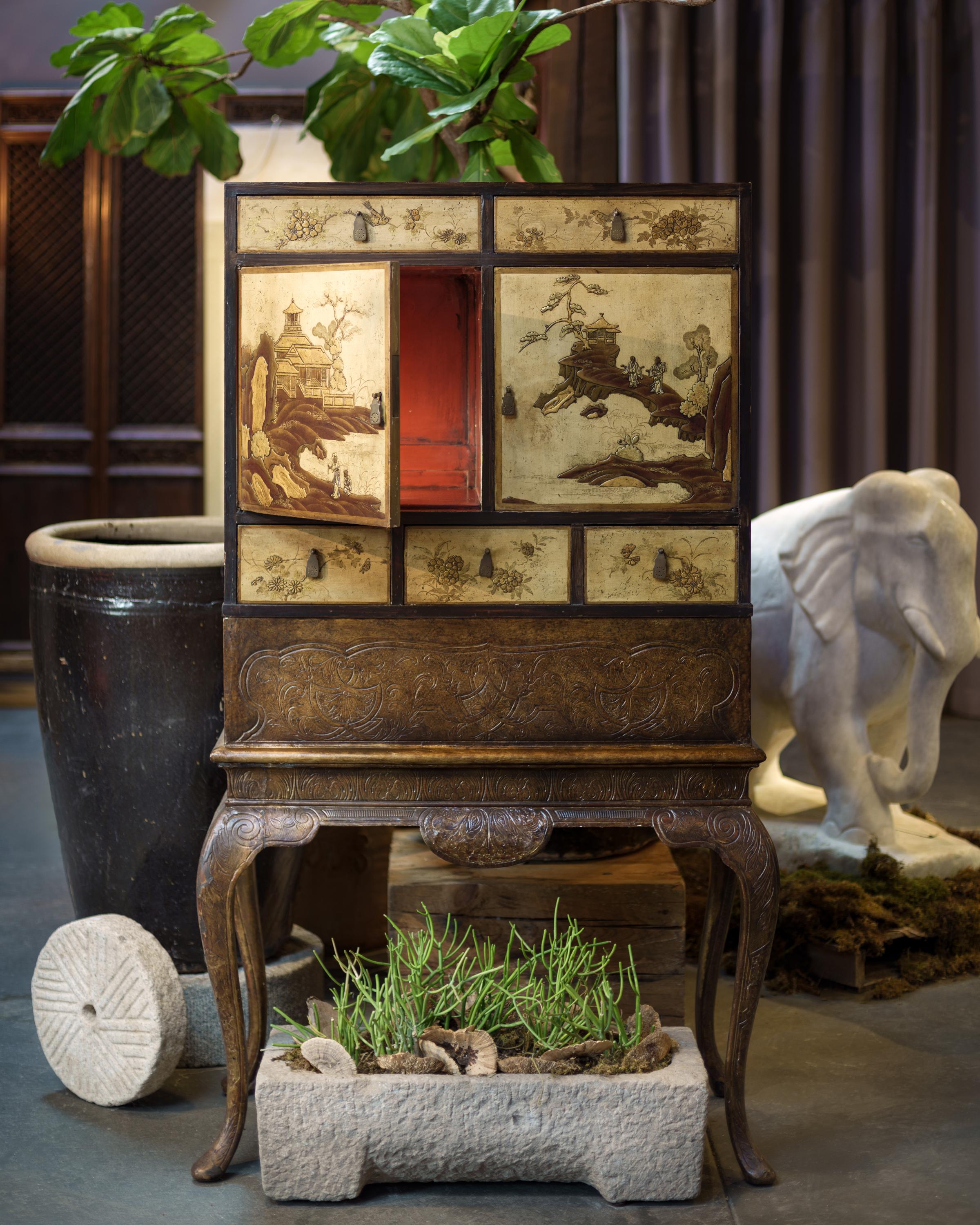 This charming cabinet-on-stand dates to the early 20th century and is decorated in the Chinoiserie style with a gilt and polychromed finish. The upper cabinet is decorated to resemble Chinese lacquer cabinetry, the doors and sides embellished with