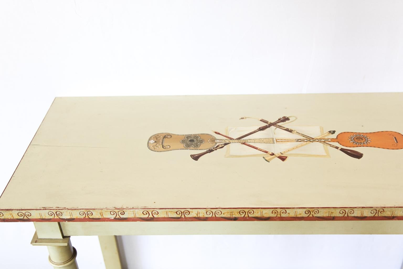 Painted console table, the top painted with very finely detailed inlaid string and reed instruments. The lower shelf is decorated with painted arabesques, and the front feet are carved scrolls.