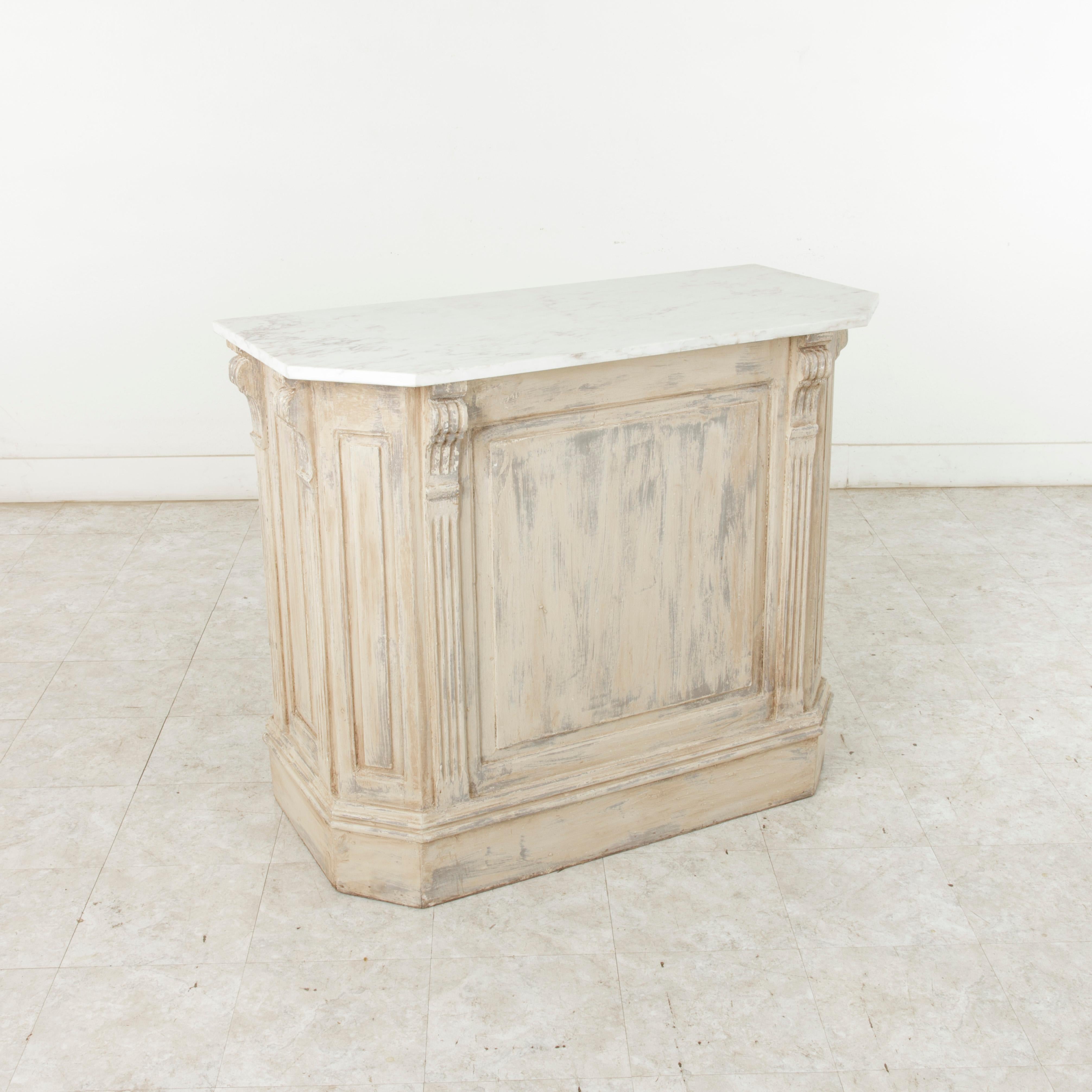 Found in Belgium, this painted counter features a veined white marble top. Six fluted half-columns flank the panels of each side of the cabinet. Two shelves at the backside provide storage space for glassware and bottles. With its marble top and