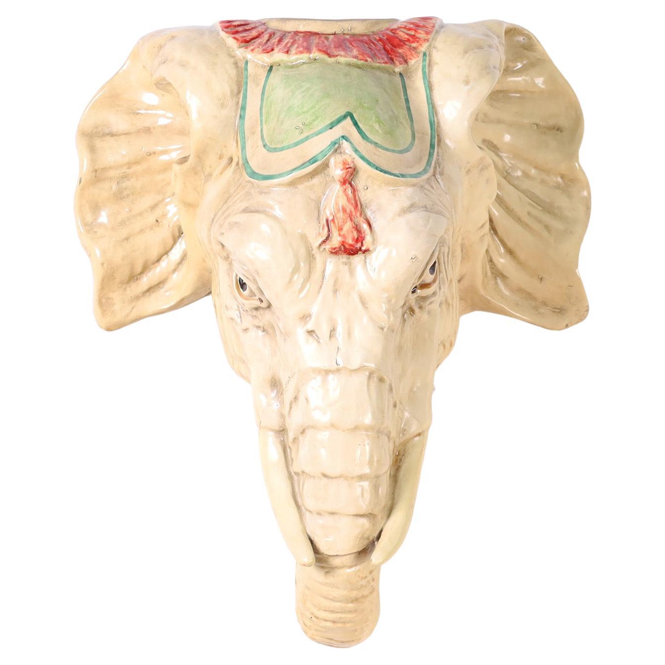 Elephant head wall sculpture crafted in composition and whimsically decorated with enamel.