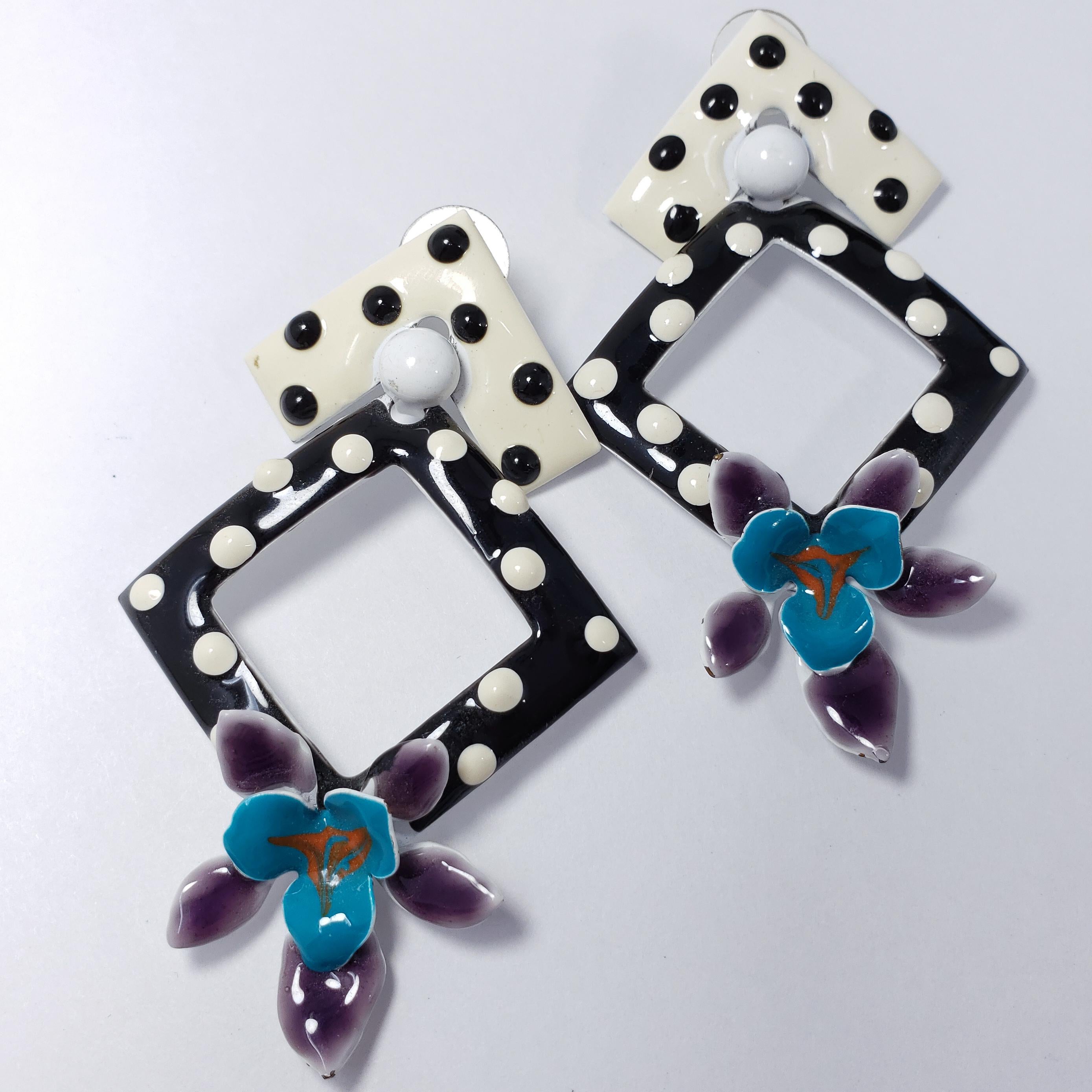 A pair of whimsical dangling earrings, featuring geometrical black and white polka-dot enamel motifs, accented with turquoise and purple flowers. Bold and stylish!