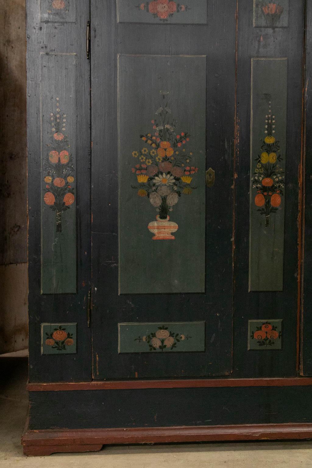 The interior of this armoire is fully open. The door's center panel and stiles are painted with floral decoration. The name and date is painted in the frieze. The right hand door has had a crack repaired. The sides are also painted with three floral