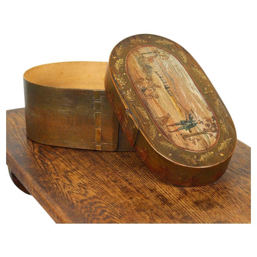 Preciosa caja antigua de madera curvada del siglo XIX, originaria del sur de Alemania. La caja está ricamente decorada con pinturas de estilo folclórico que representan una animada escena de caza, lo que le confiere un carácter decorativo único.