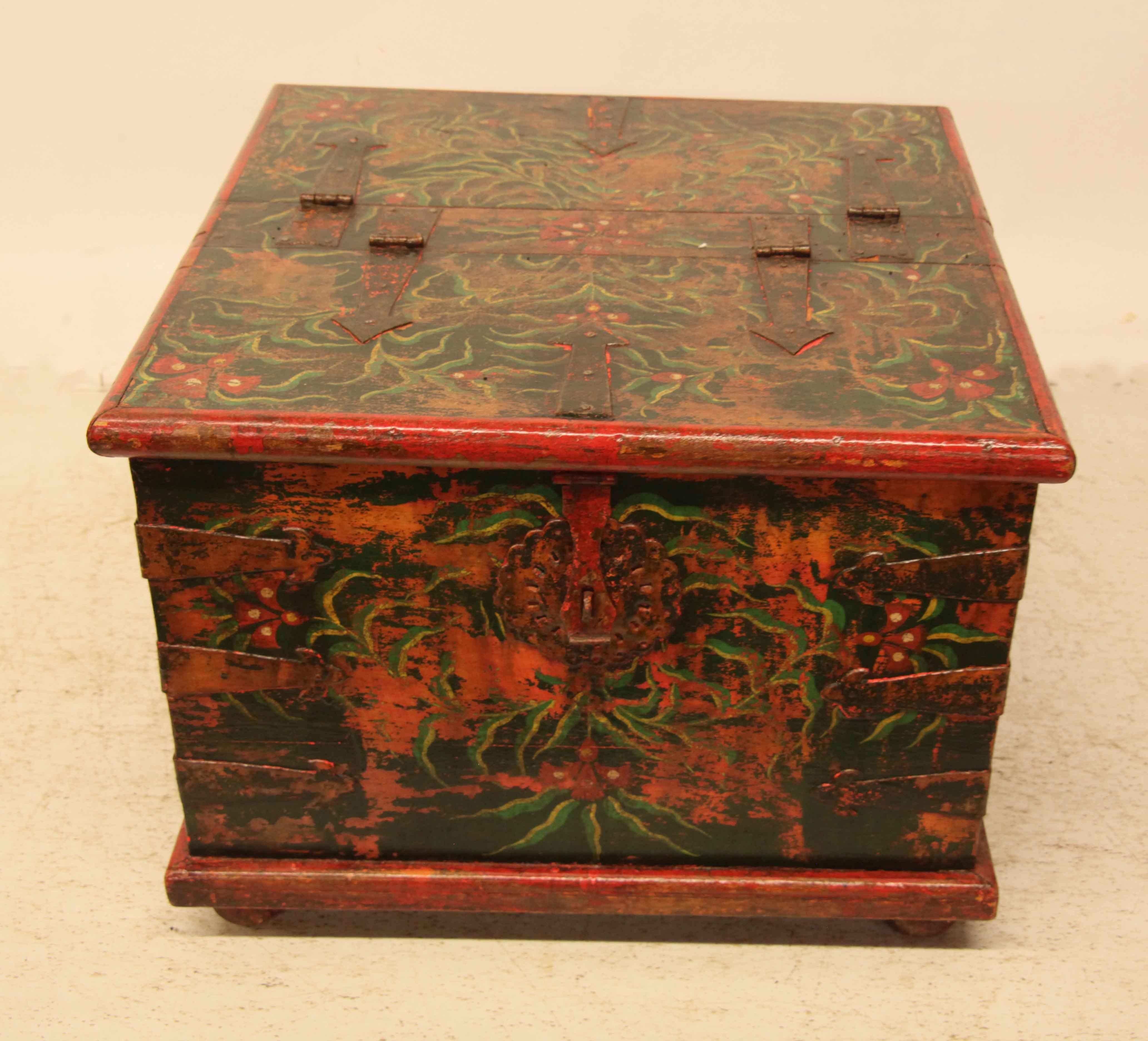 Painted four sided box, the top is split and hinged on each half to allow access from both sides; all sides and top with similar decorative and vivid painting featuring stylized flowers and foliate. The two sides that open have a reticulated round
