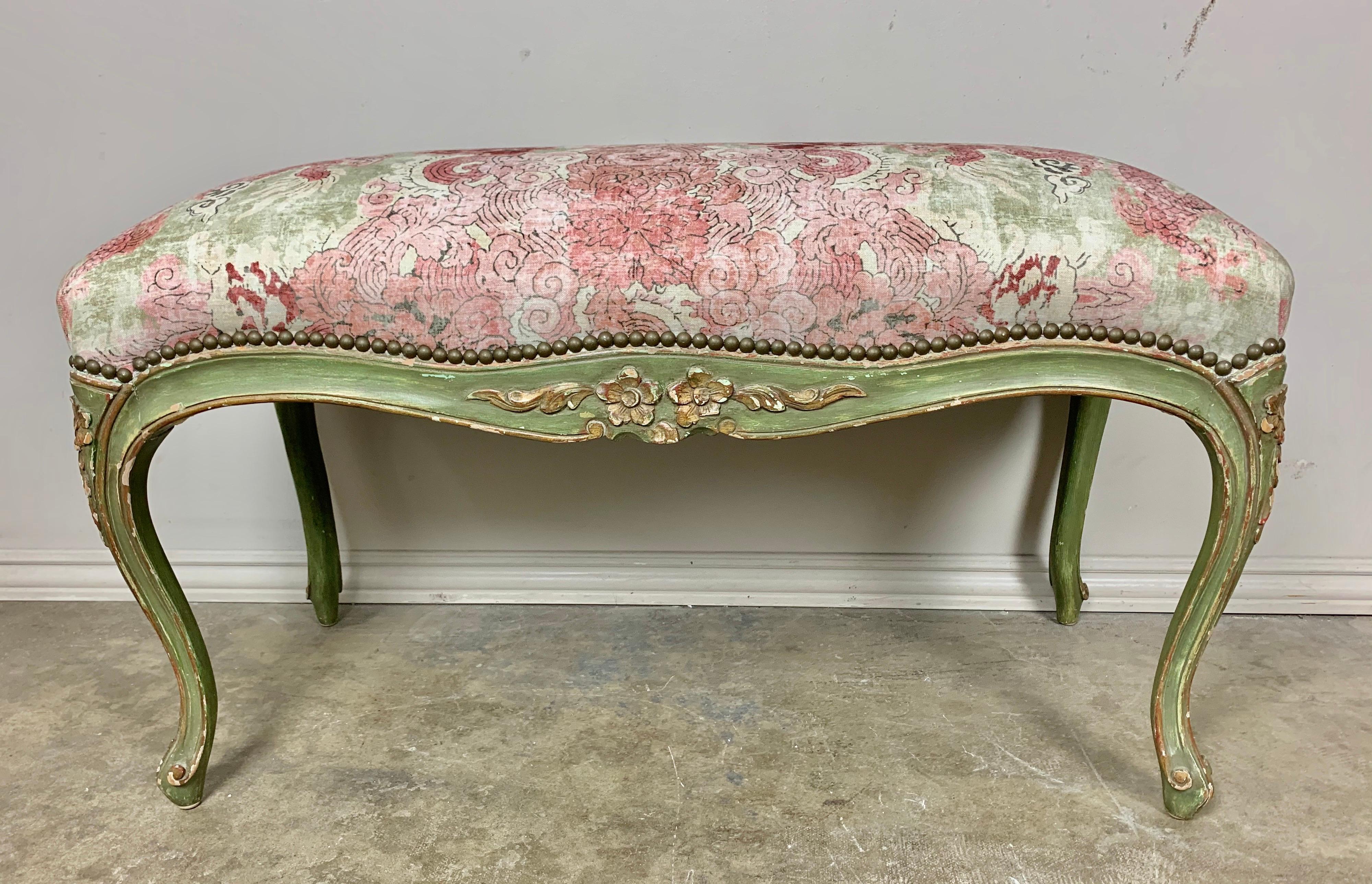 French green painted carved wood bench with carved detailed flowers throughput. The bench stands on four cabriole legs with rams head feet and is newly upholstered in a printed cotton with a whimsical dragon chinoiserie design. Nail head trim detail.
