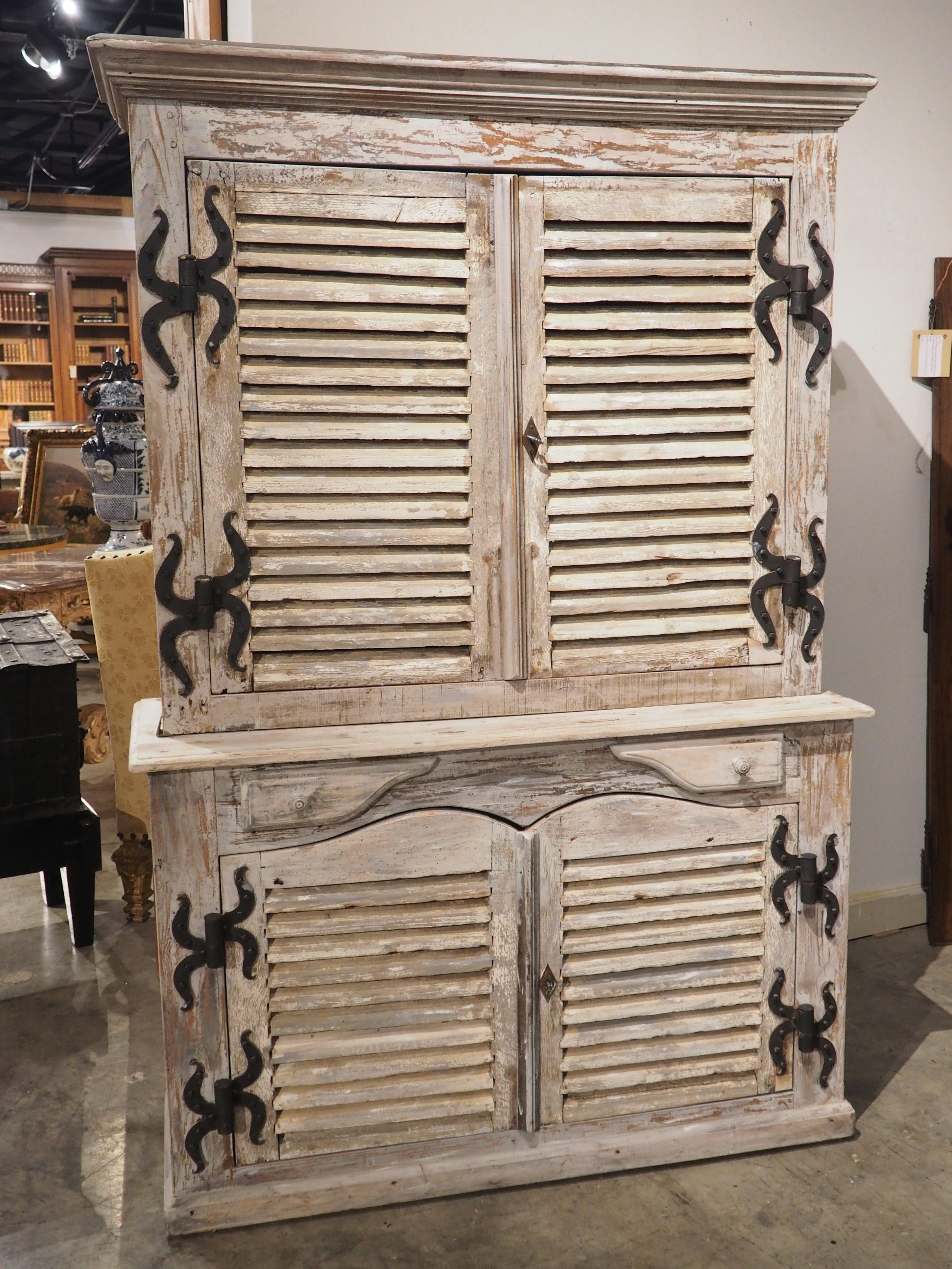 Assembled by a French artisan, this painted buffet has incorporated two pairs of antique shutter doors into the deux corps (two bodies) construction. The shutter doors open on four pintel hinges with uniquely shaped iron mounts. Both doors are