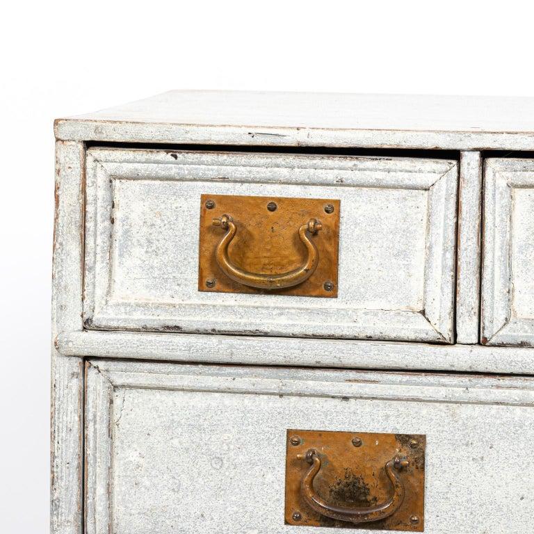 Painted French commode with six drawers and oversized brass hardware, circa 1890s. The piece also features bun turned feet. Please note of wear consistent with age including paint loss.