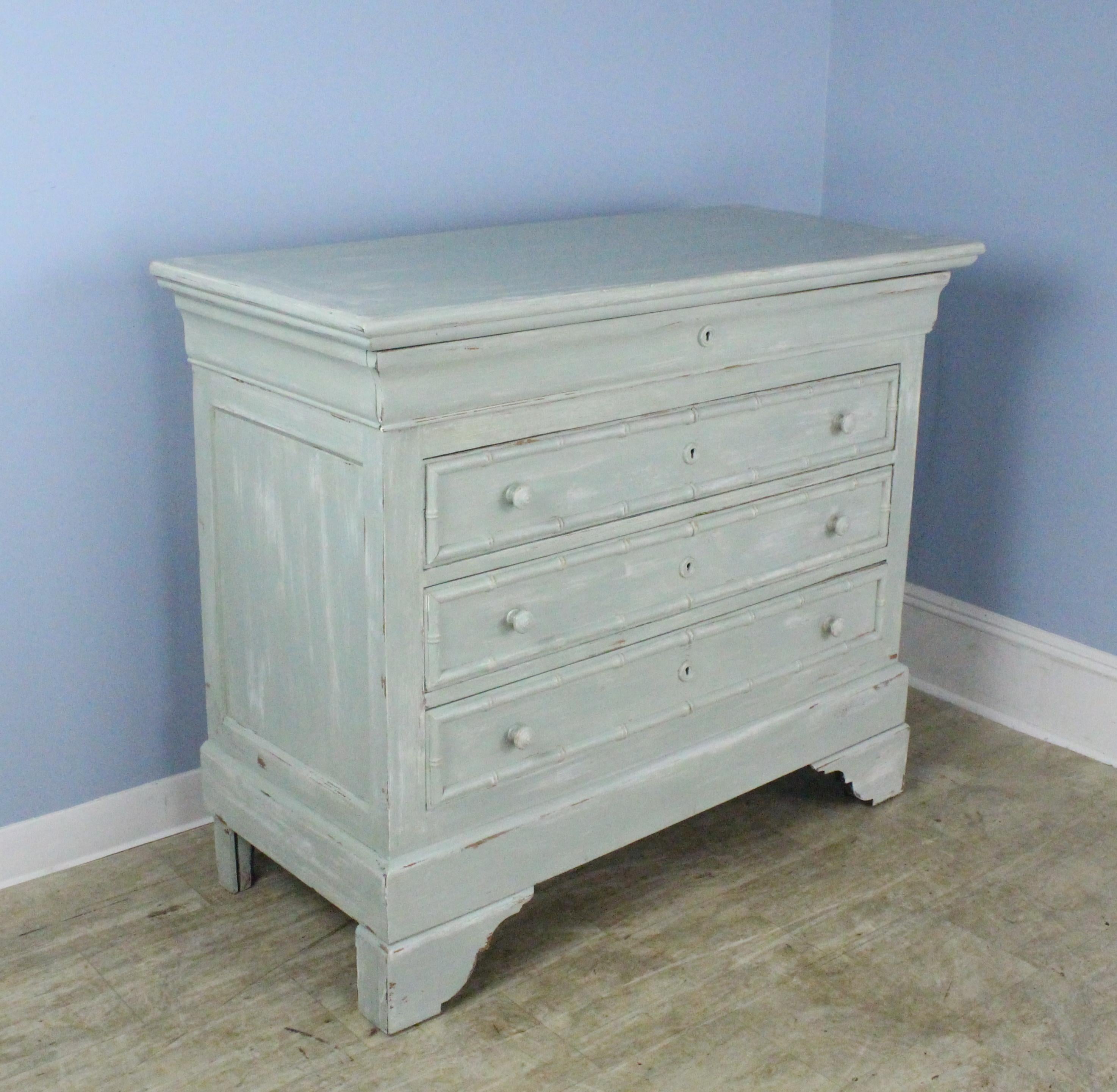 A French pine faux bamboo chest of drawers in the Louis Philippe style, newly painted and faux distressed in a fanciful blue green. Drawers run nicely, and are still lined with the original paper. Heavy and sturdy.
