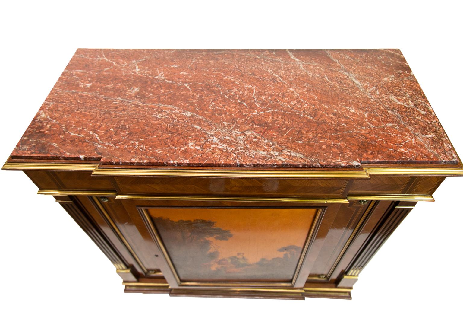 The marble top of this painted French inlaid console cabinet is framed with shaped brass molding. The frieze has bookmatched herringbone inlaid panels framed by boxwood and ebony line inlays. There is raised brass molding below the frieze. The