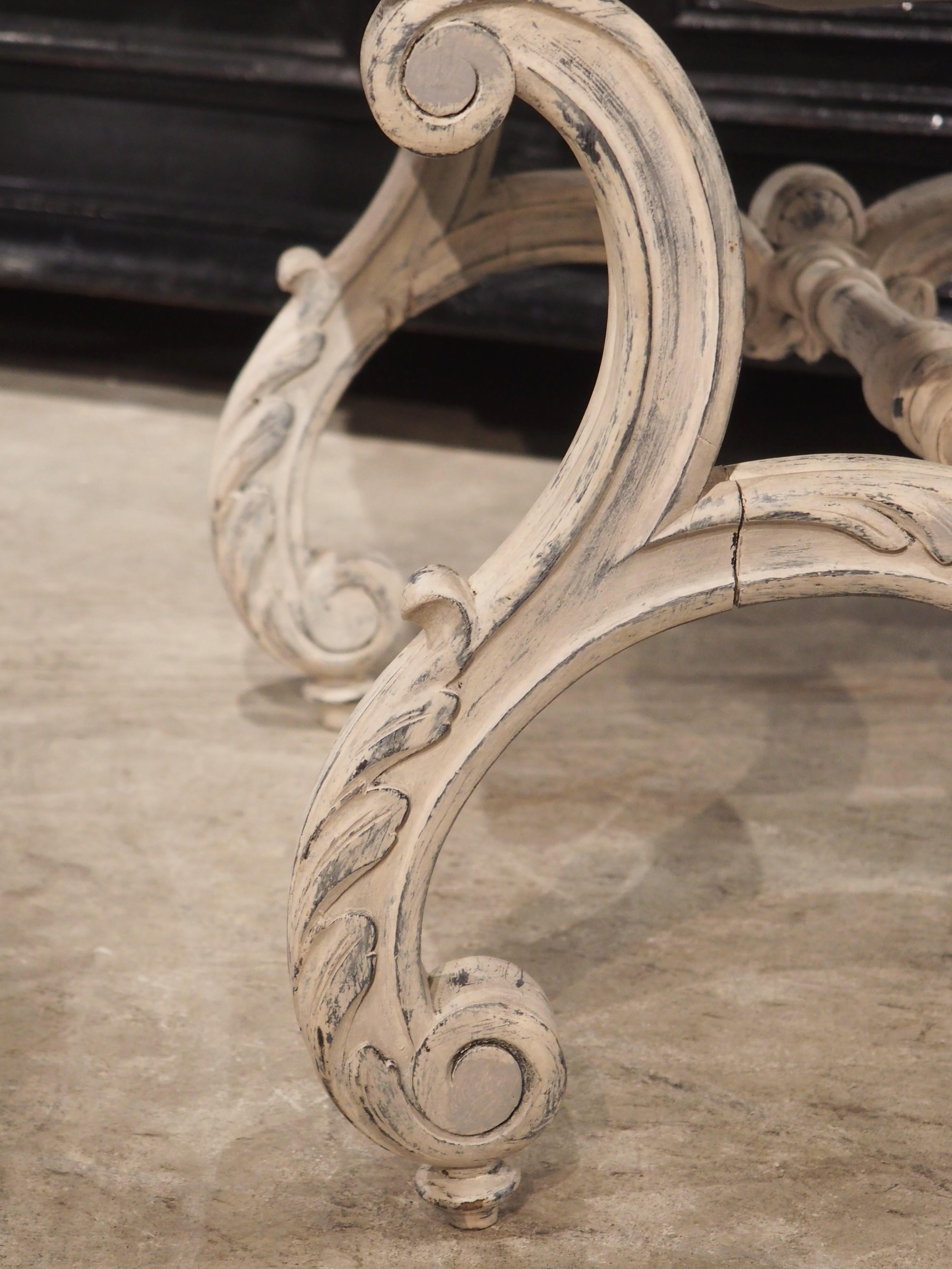 This painted French tabouret was hand-carved circa 1900 in the style of Louis XV and topped with a floral upholstery affixed by several brass nailheads. The wood base has a parcel gray and blue finish and is comprised of four S-scroll legs, each