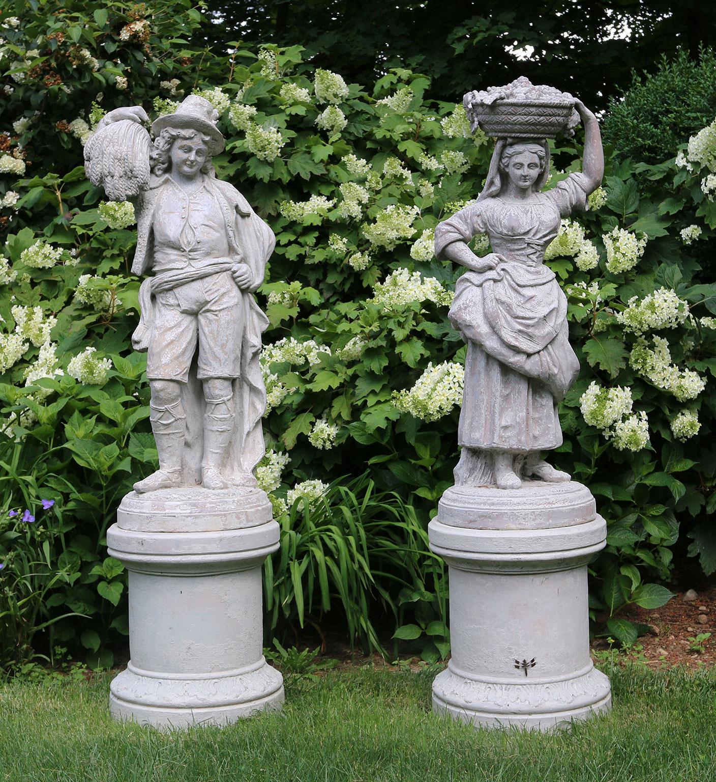 A pair of stoneware pastoral figures on cylindrical pedestals, the male figure in peasant dress with sheaf of wheat on proper right shoulder and the female figure, also in rustic dress, with a basket of fruit upon her head,
French, circa 1890.
