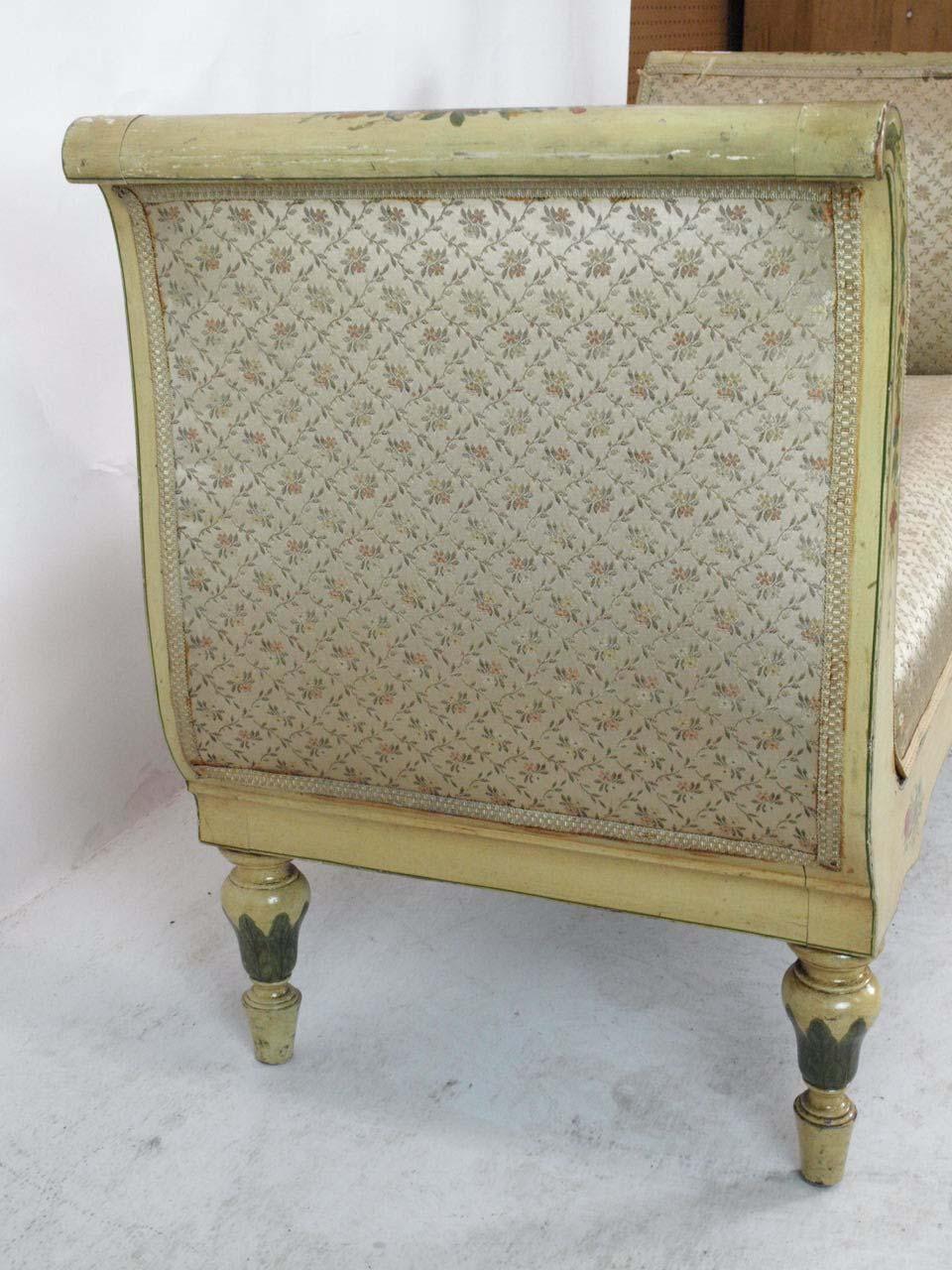 Painted French window bench, with floral and leaf painted decoration on both sides, the S shaped ends and lower rail with similar painting. The entirety painted a warm cream color with a yellow tint, upholstered seat and sides is in fair condition,