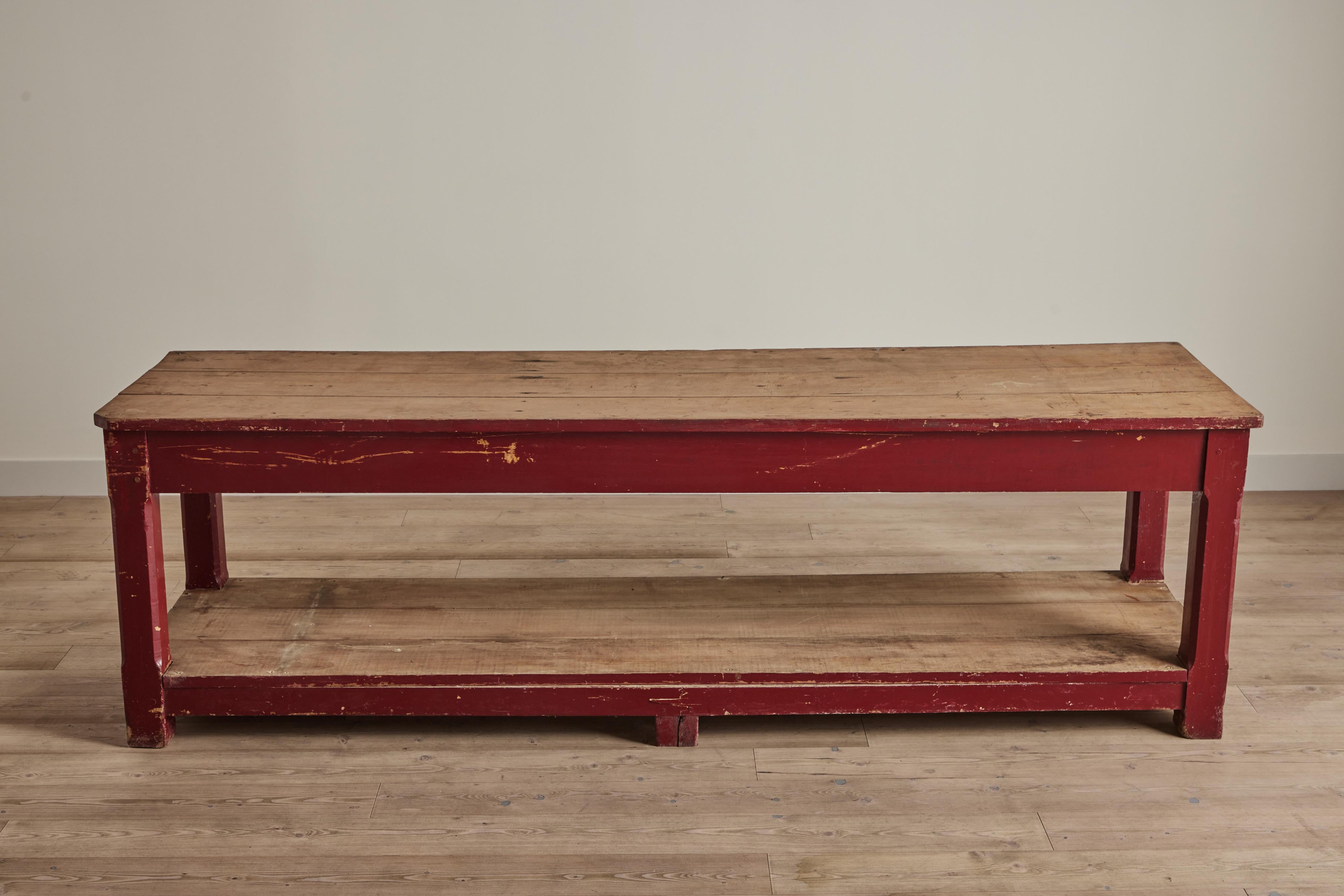 Painted red general store wood table with lower shelf, United States circa 1900. Wear throughout on painted finish and wood that is consistent with age and use.