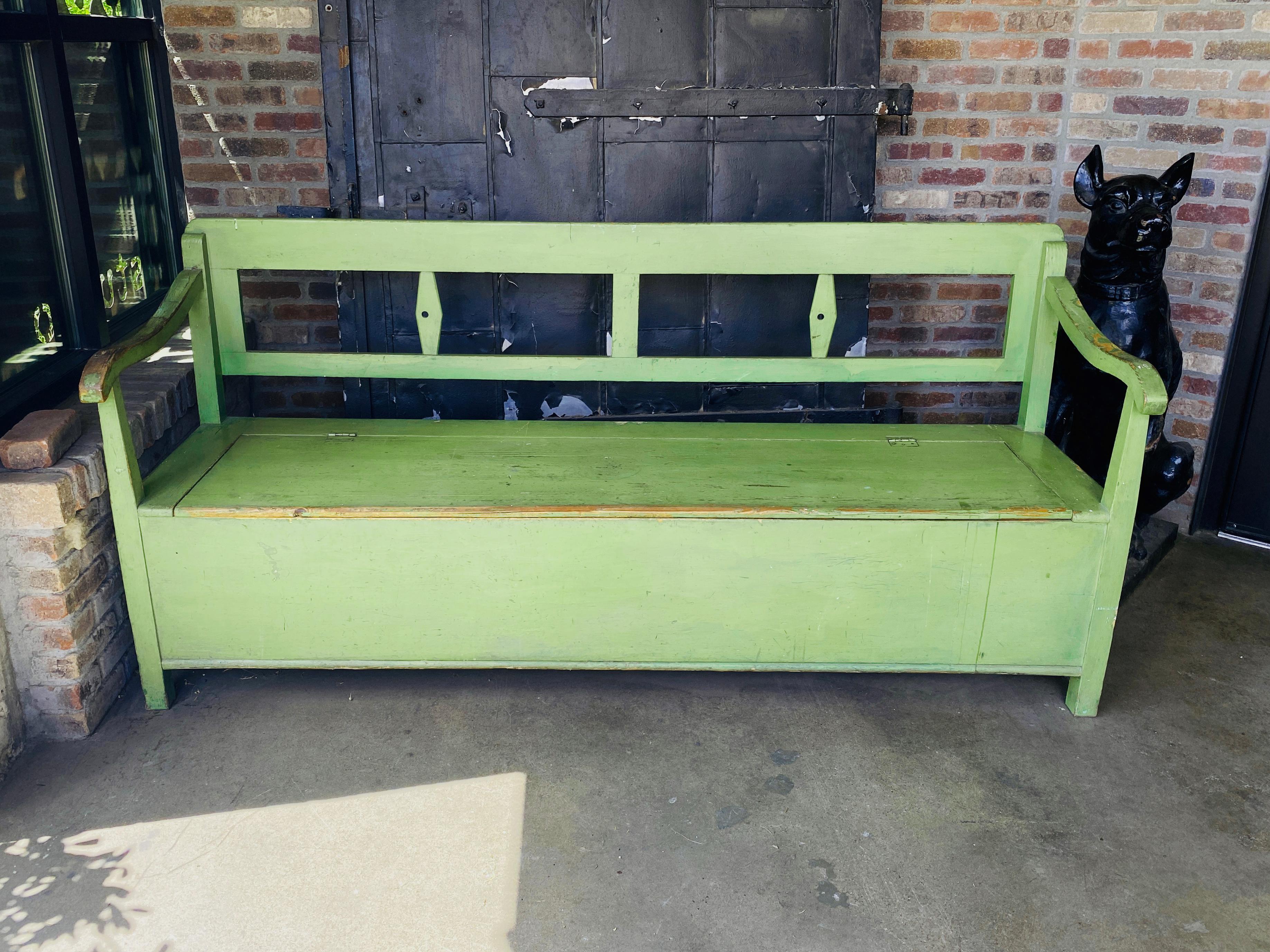 Extraordinary color and scale…and secret storage too! Painted wood bench with backrest and arms. Seat opens to reveal storage. Excellent for shoes and boots in an entry hall or mud room or as a blanket chest or toy chest. Well worn paint has patina