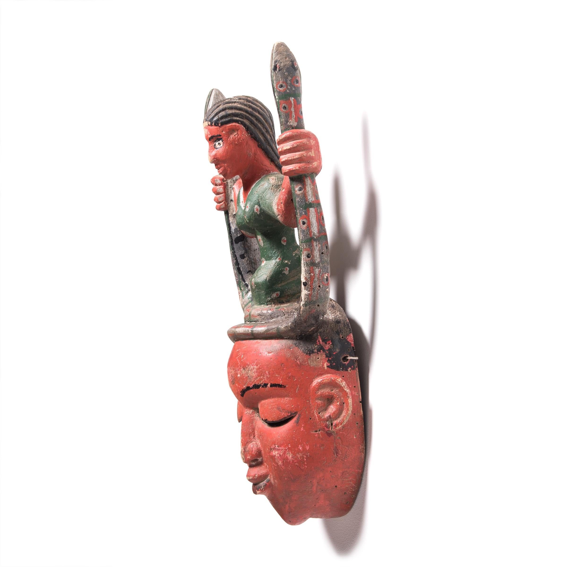 This brightly-colored painted mask is a dance mask attributed to the Guro peoples of Côte d'Ivoire. The mask depicts Mami Wata, or 
