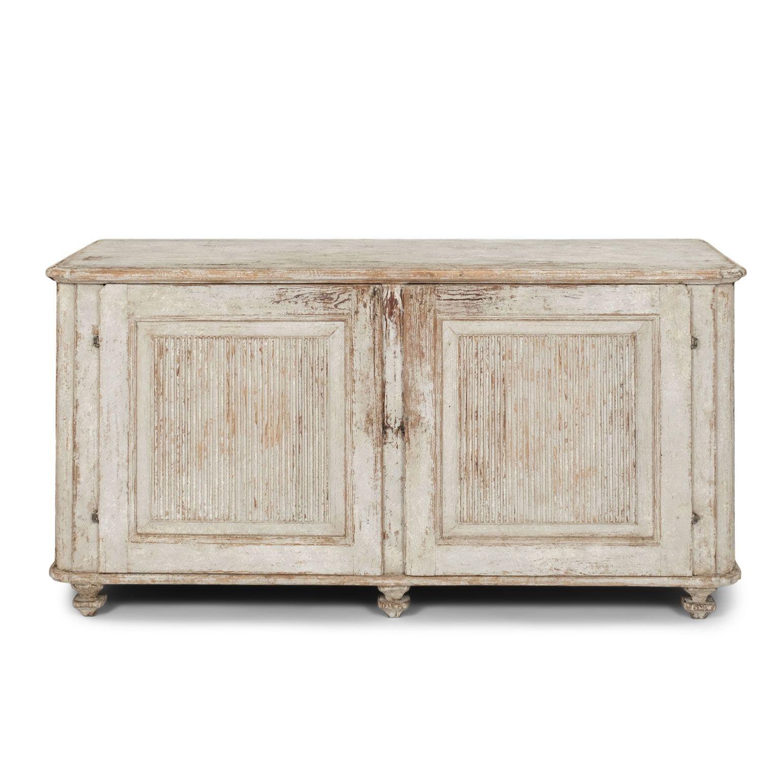 Gustavian painted buffet with reeded-paneled doors circa 1810-1829. Late Gustavian period two-door buffet in white/very light blue-gray paint. Doors paneled in hand-carved reeding.