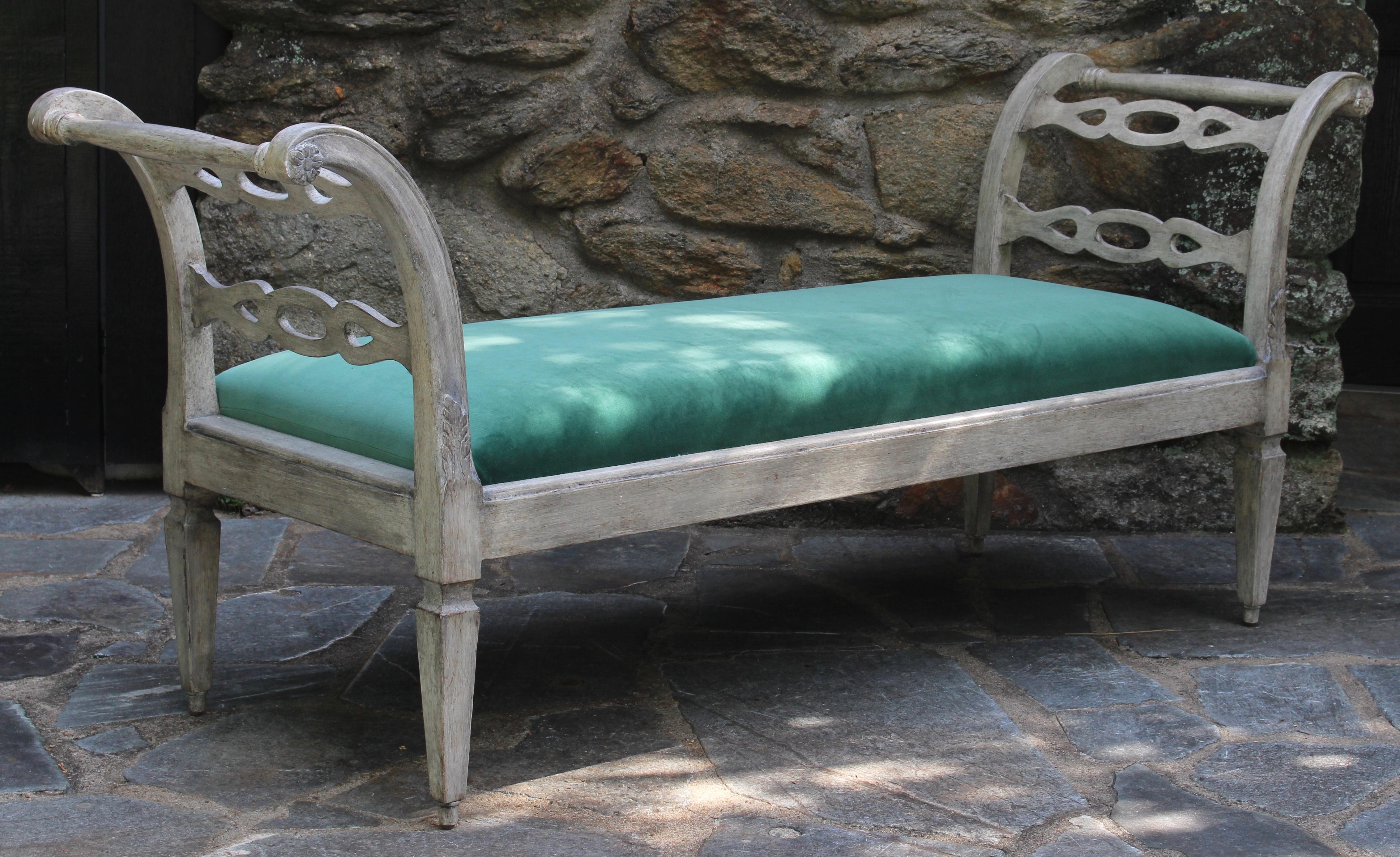 An elegant late 20th century painted and carved Gustavian style bench or window seat upholstered in an emerald green velvet.