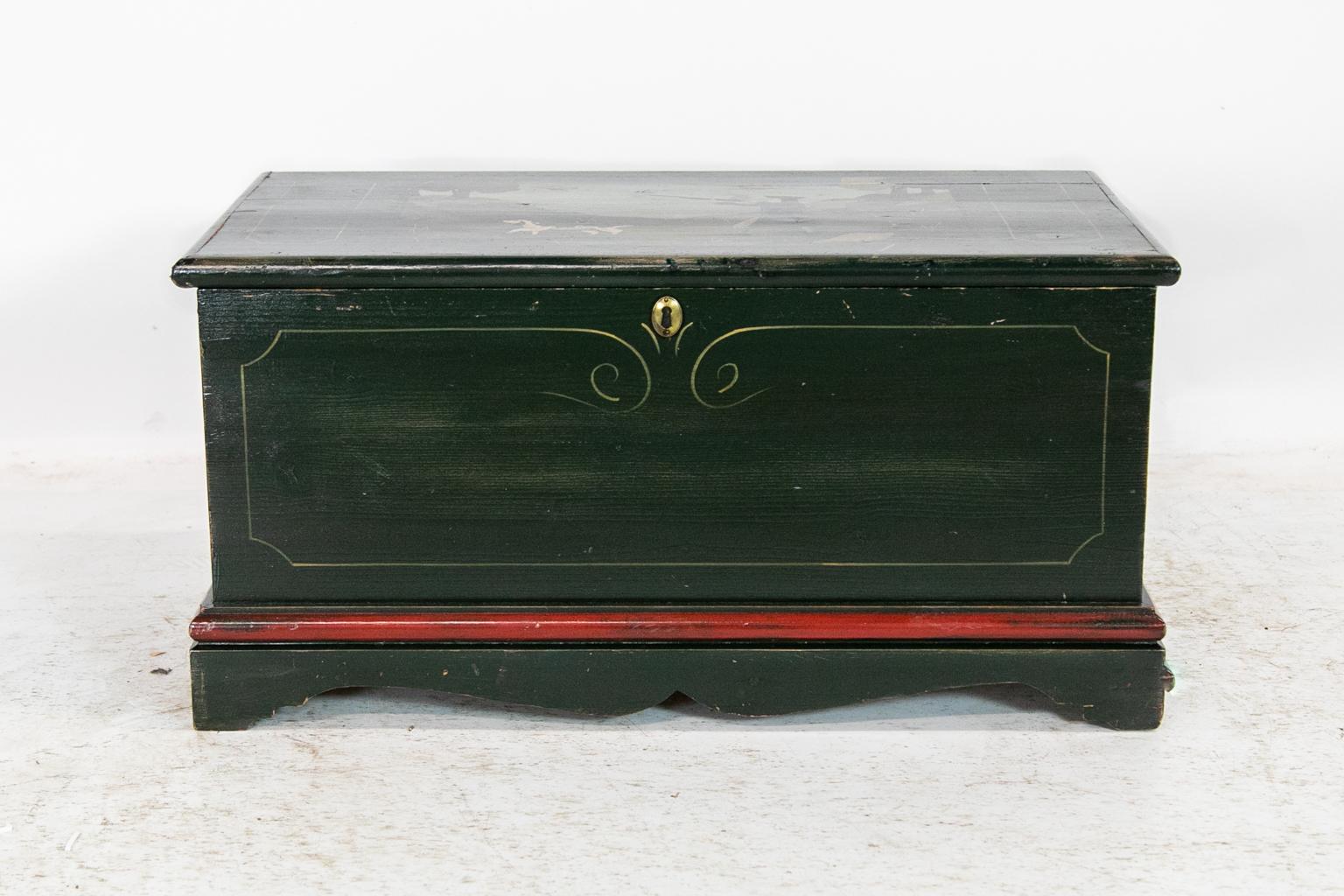 This blanket chest is painted with a scene of an 18th century gentleman hunting with his bird dog. The front is painted with simulated line inlay. The base has a reddish brown molding above the bracket feet.
  