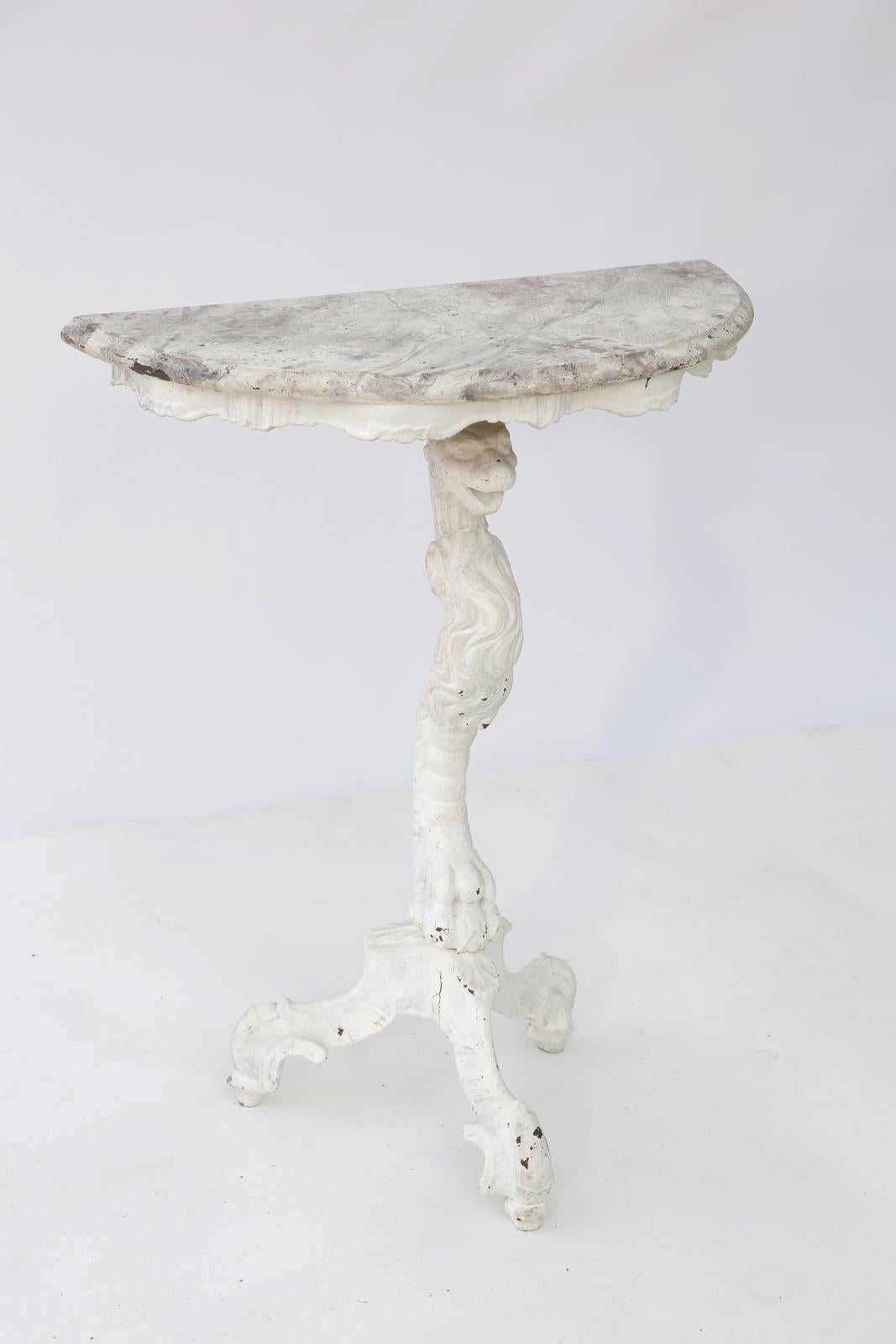 Demilune console table having a faux painted, molded top, over the painted pedestal base, showing natural wear, hand carved as a smiling wildcat, with 