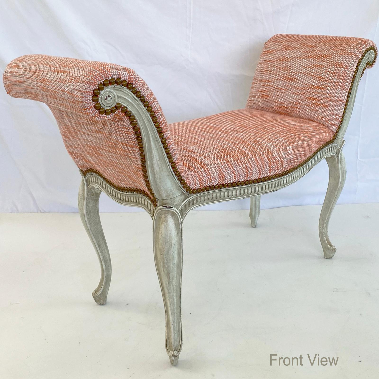 Window seat, upholstered in coral twill fabric with nailheads, having exaggerated scrolling arms, its painted frame inset into the front-facing arms, bowed front crown seat set upon its shaped fluted apron, raised on cabriole legs, ending in scroll