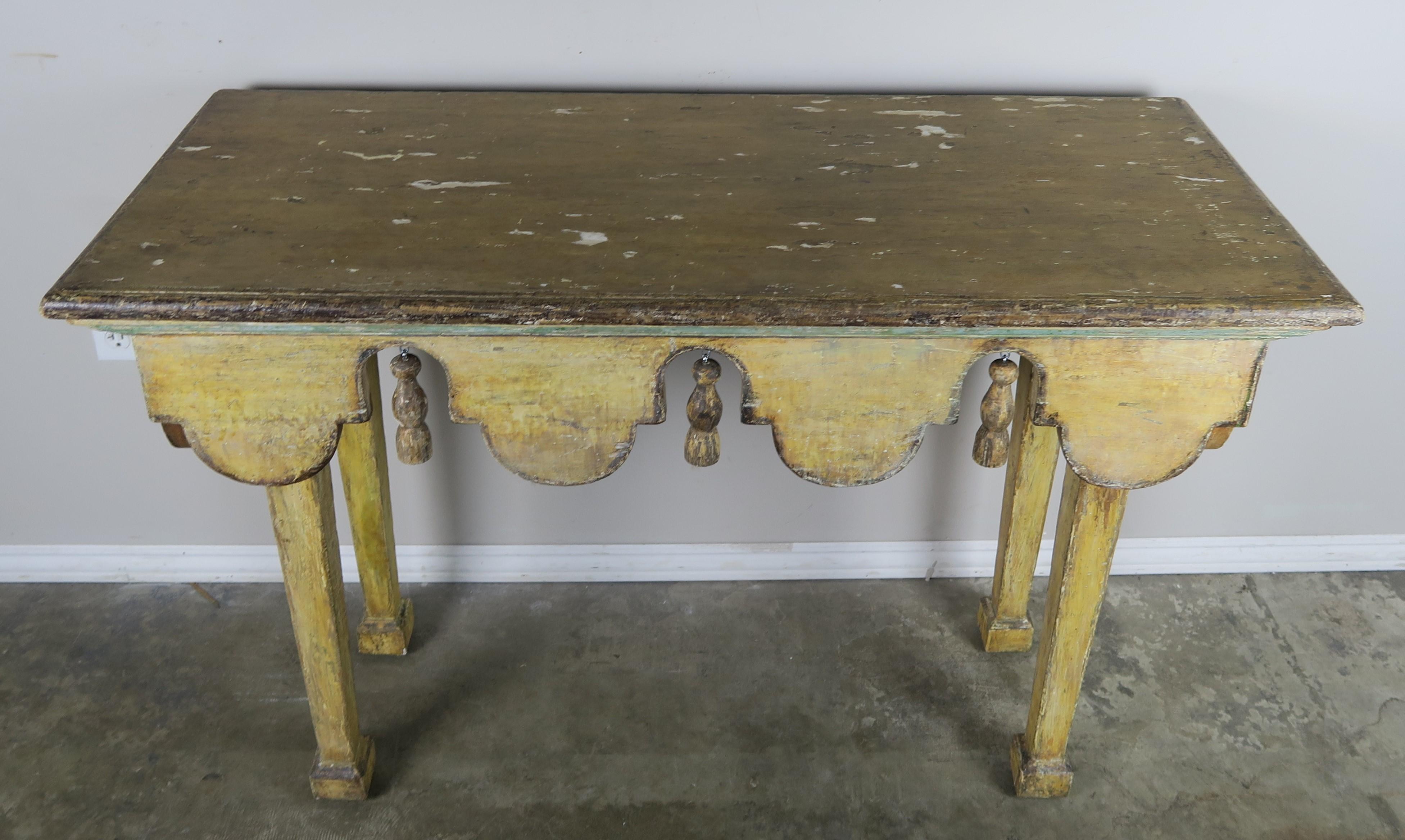 Painted Italian midcentury table with swags and carved tassels hanging between each swag. The table stands on four straight tapered legs. The paint is beautifully distressed with the natural wood showing underneath in areas.