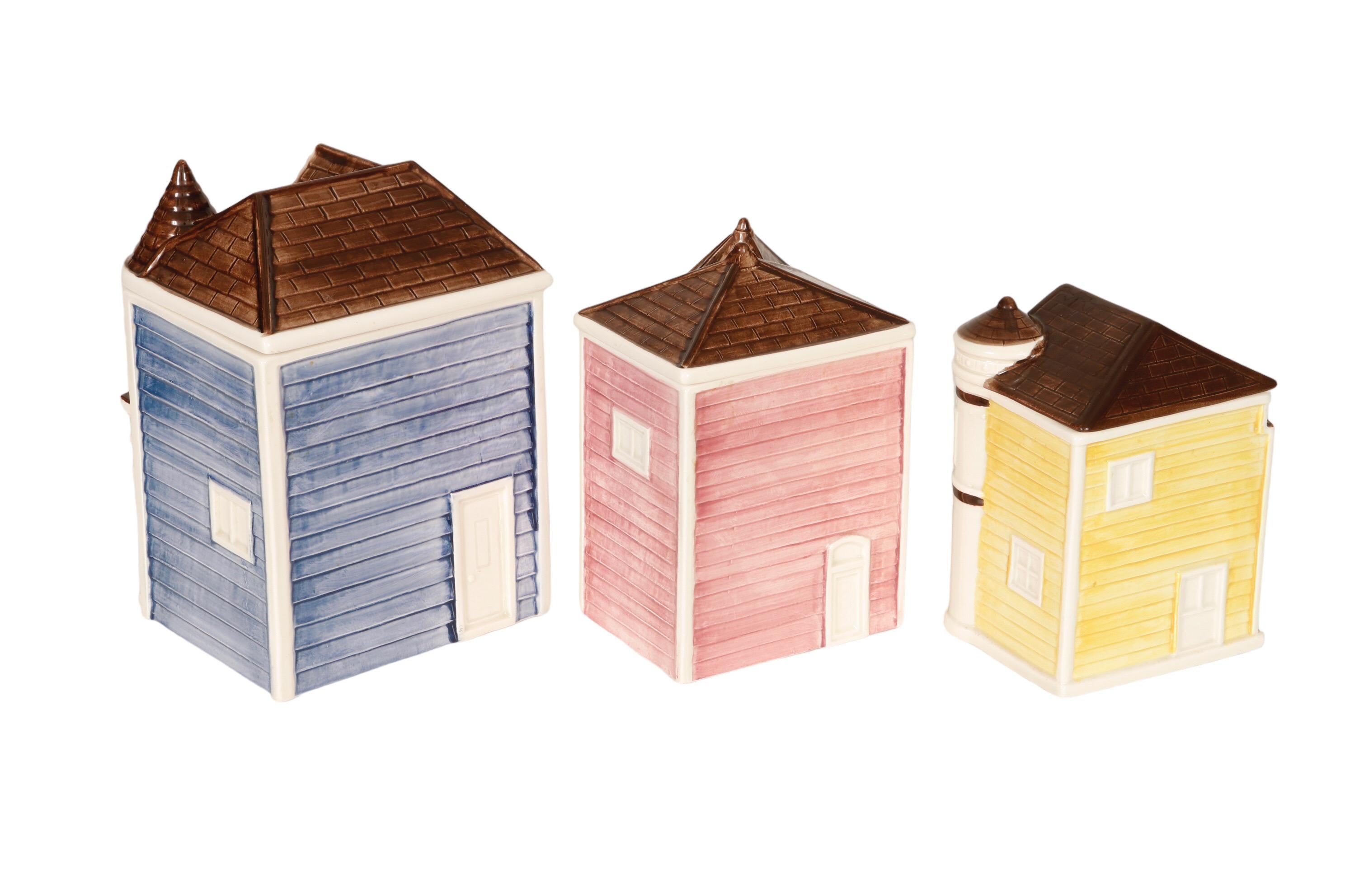 A set of three hand painted ceramic kitchen canisters in the style of Victorian “Painted Lady” houses, made by Otagiri of Japan. Brightly colored in powder blue, pink, and yellow. Marked ‘Otagiri Hand Painted made in Japan’ underneath. Canisters