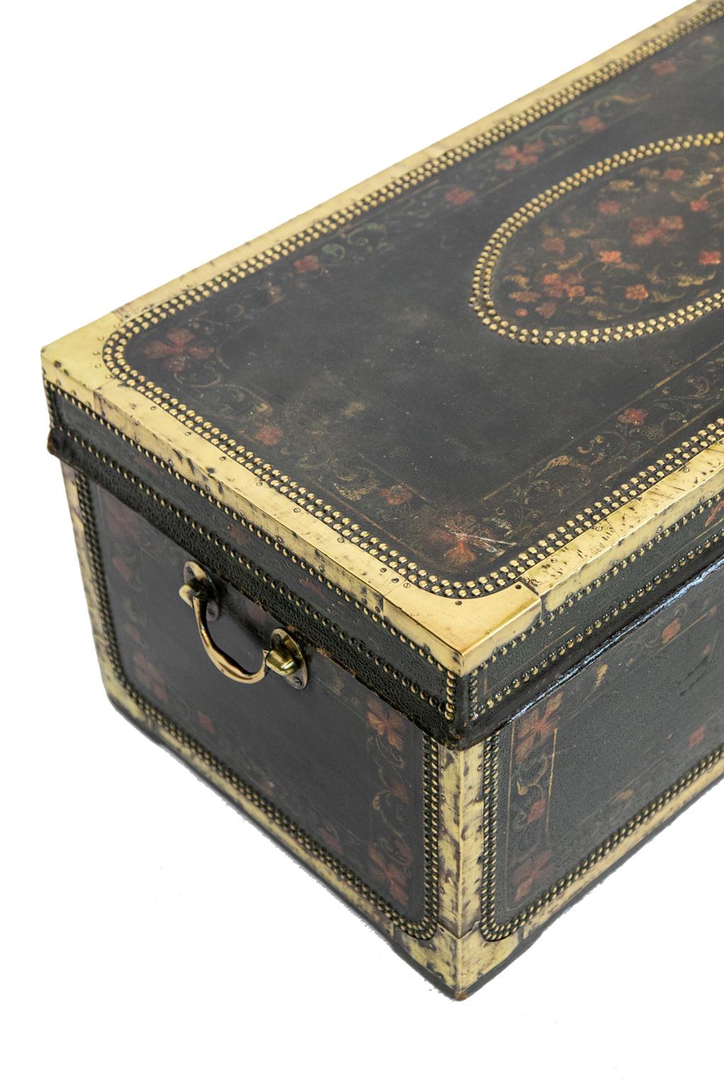 Painted leather camphor wood trunk, the top is double brass studded with brass framing. It is painted with a floral center cartouche and borders and has the original brass carrying handles.