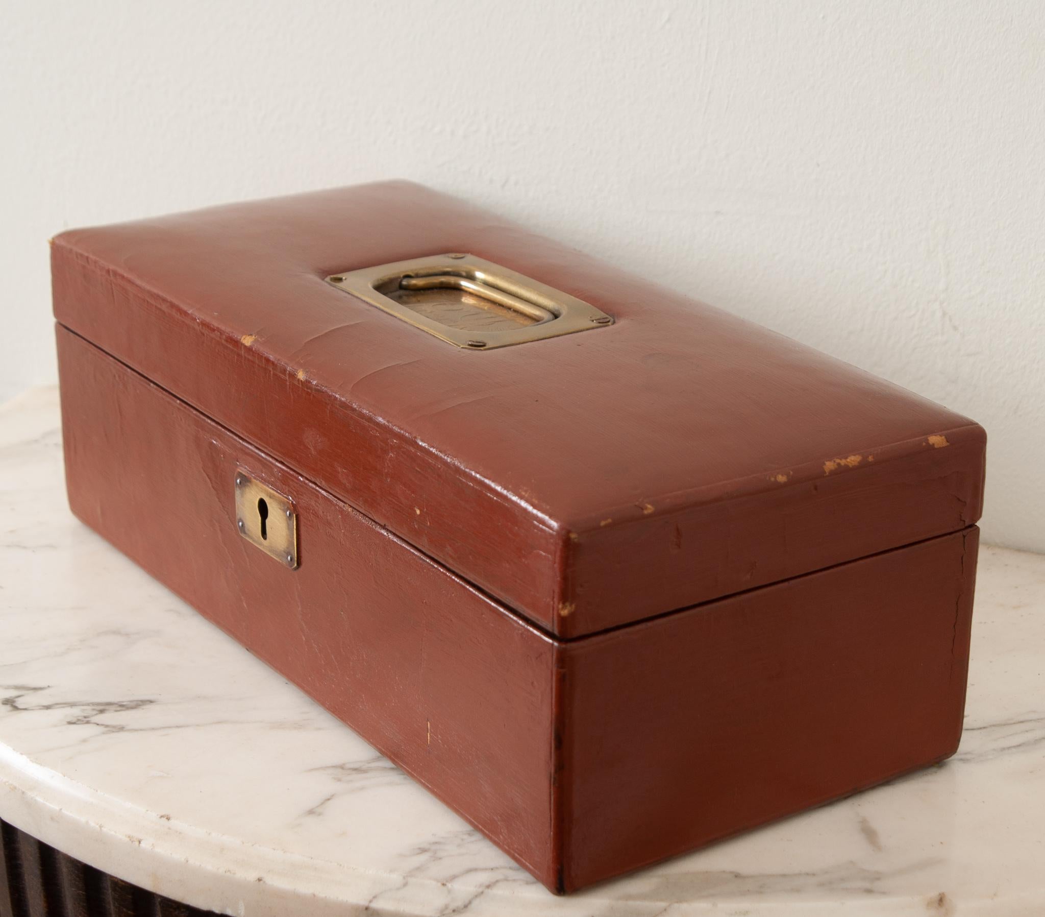 A French painted leather jewelry box with an inset brass handle custom monogrammed “EU, January, 24, 1898”. Inside you’ll find the box is fitted for storing jewelry with two levels of lined storage compartments, all upholstered in a rich red fabric.
