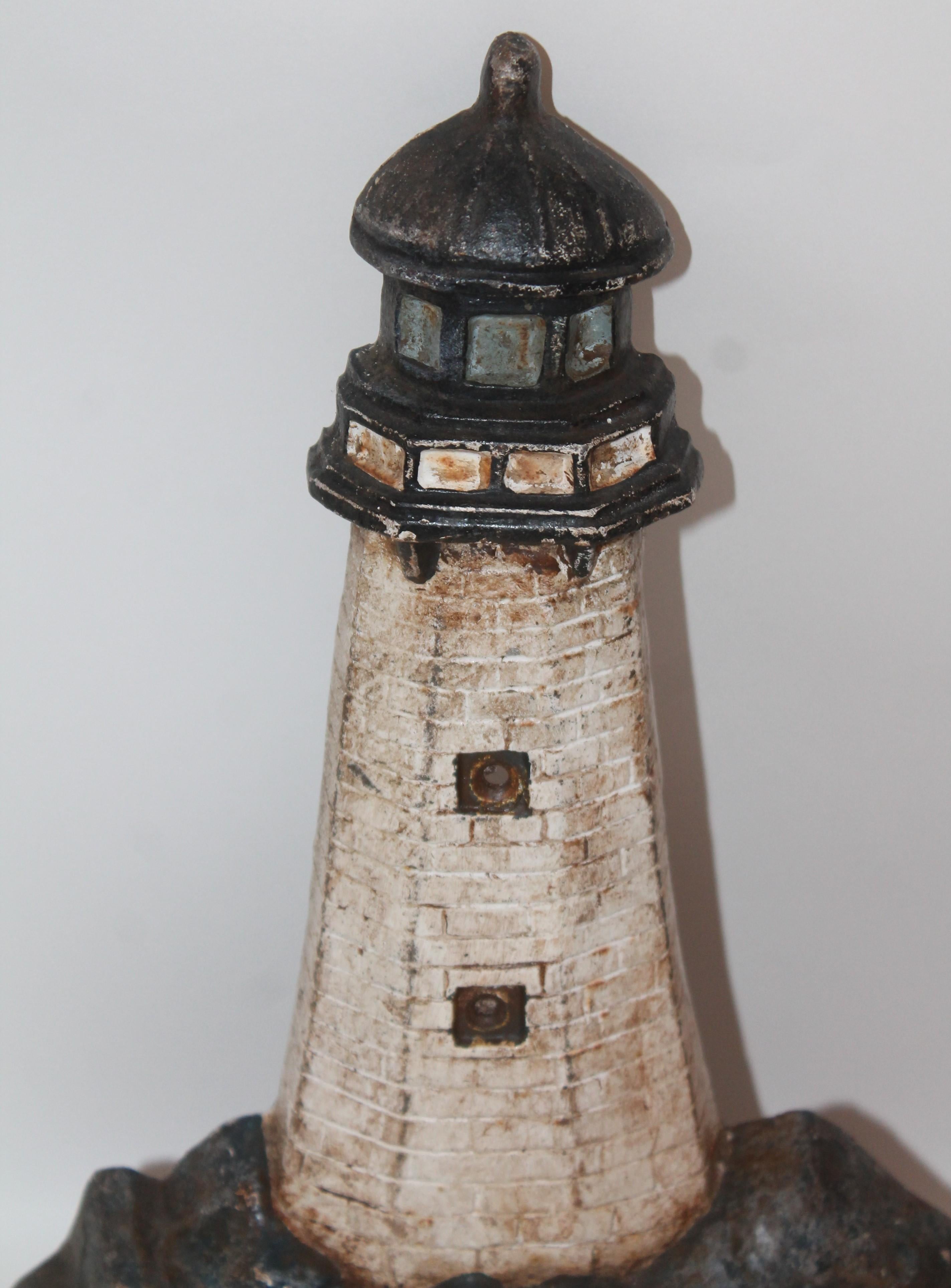 This great painted cast iron lighthouse door stop is in good condition with wear consistent from age and use. This door stop has holes in the windows for light to come or shine through.
