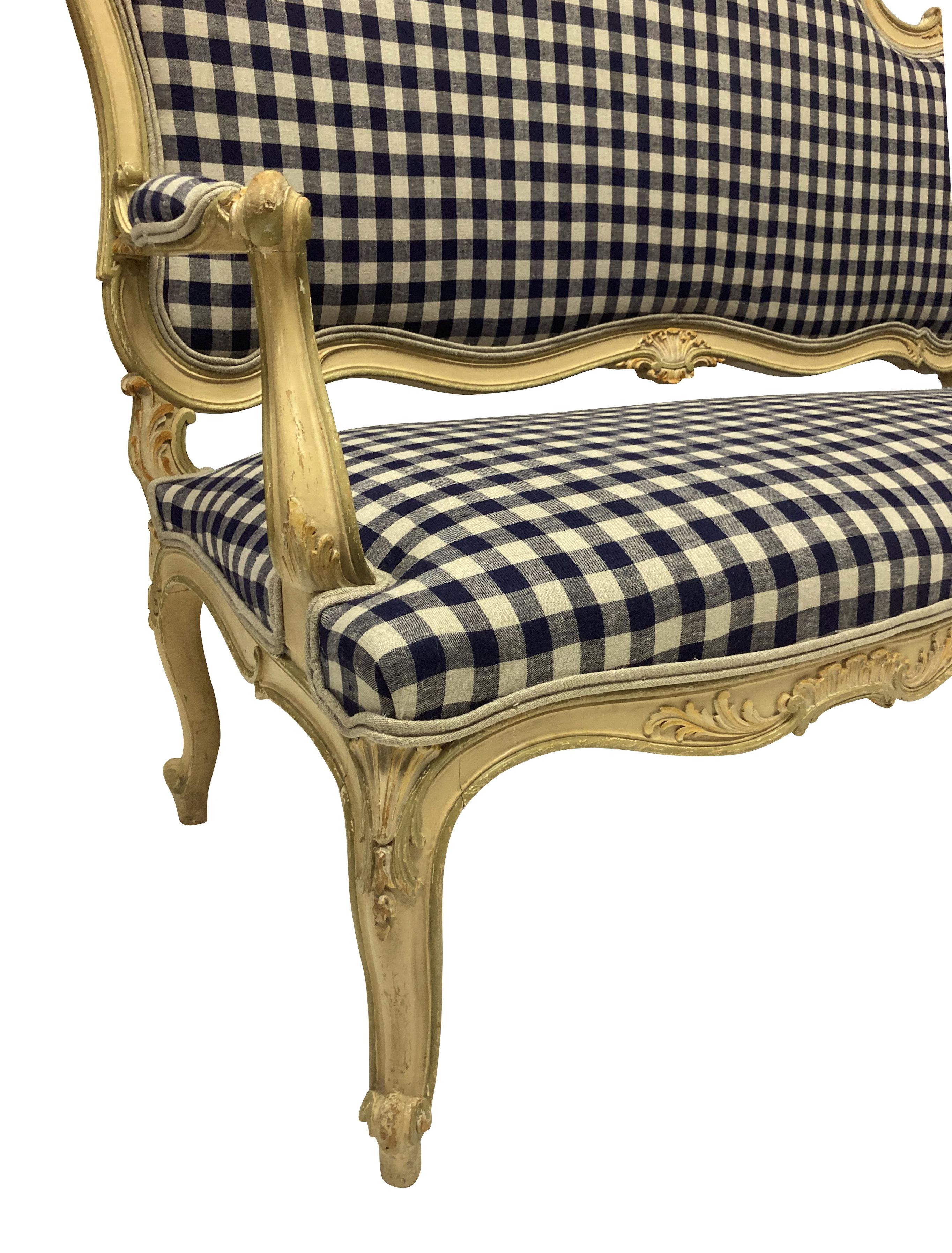 A French carved and painted Louis XV style canape, in subtle greens and yellows, newly upholstered in navy gingham linen.