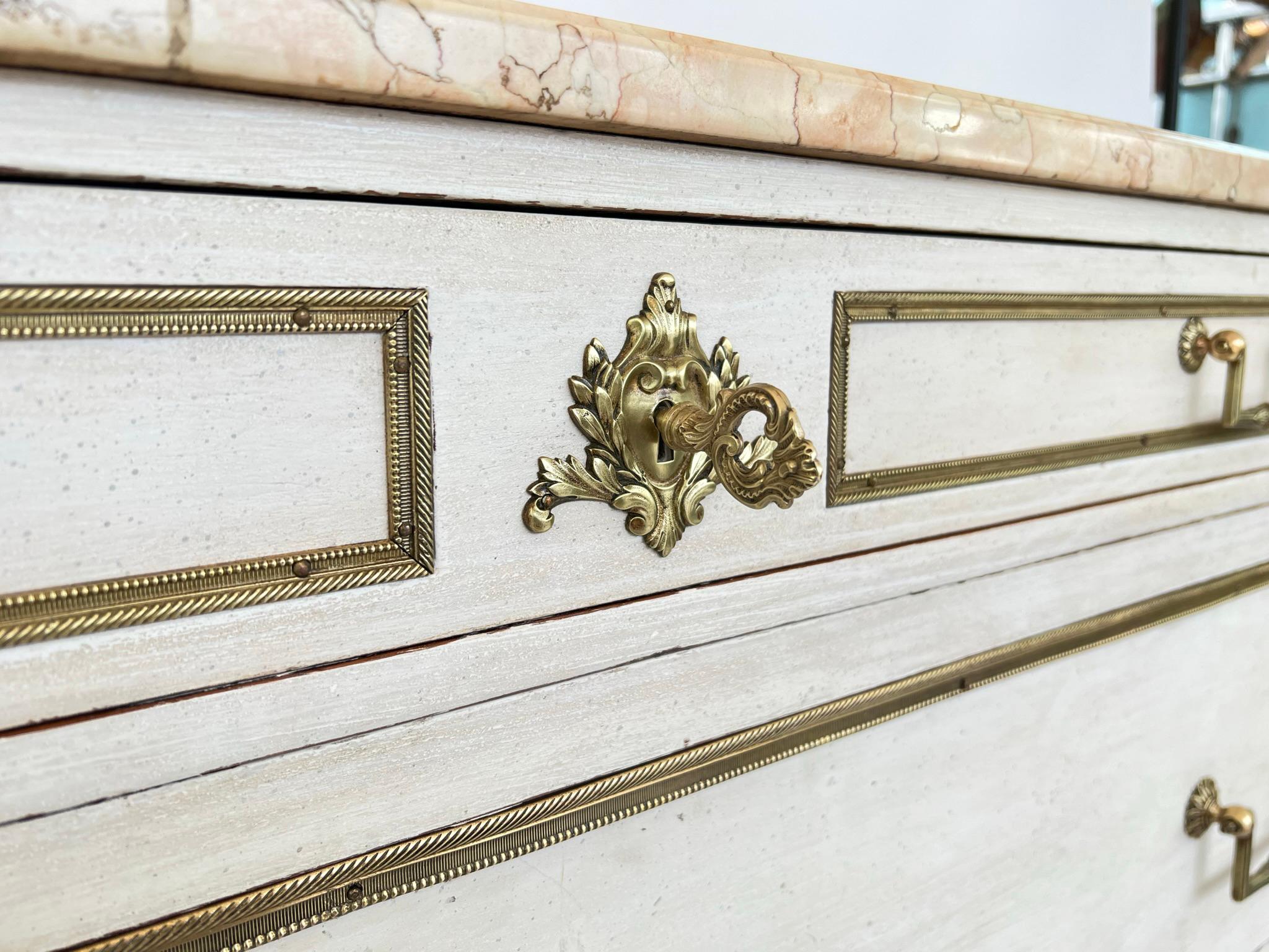 Marble above three drawers adorned with original brass trim and neoclassical drop bail brass handles and ribbon escutcheons. Supported on curved and fluted stiles raised on toupie feet ending in brass sabots.

Stock ID: D9248