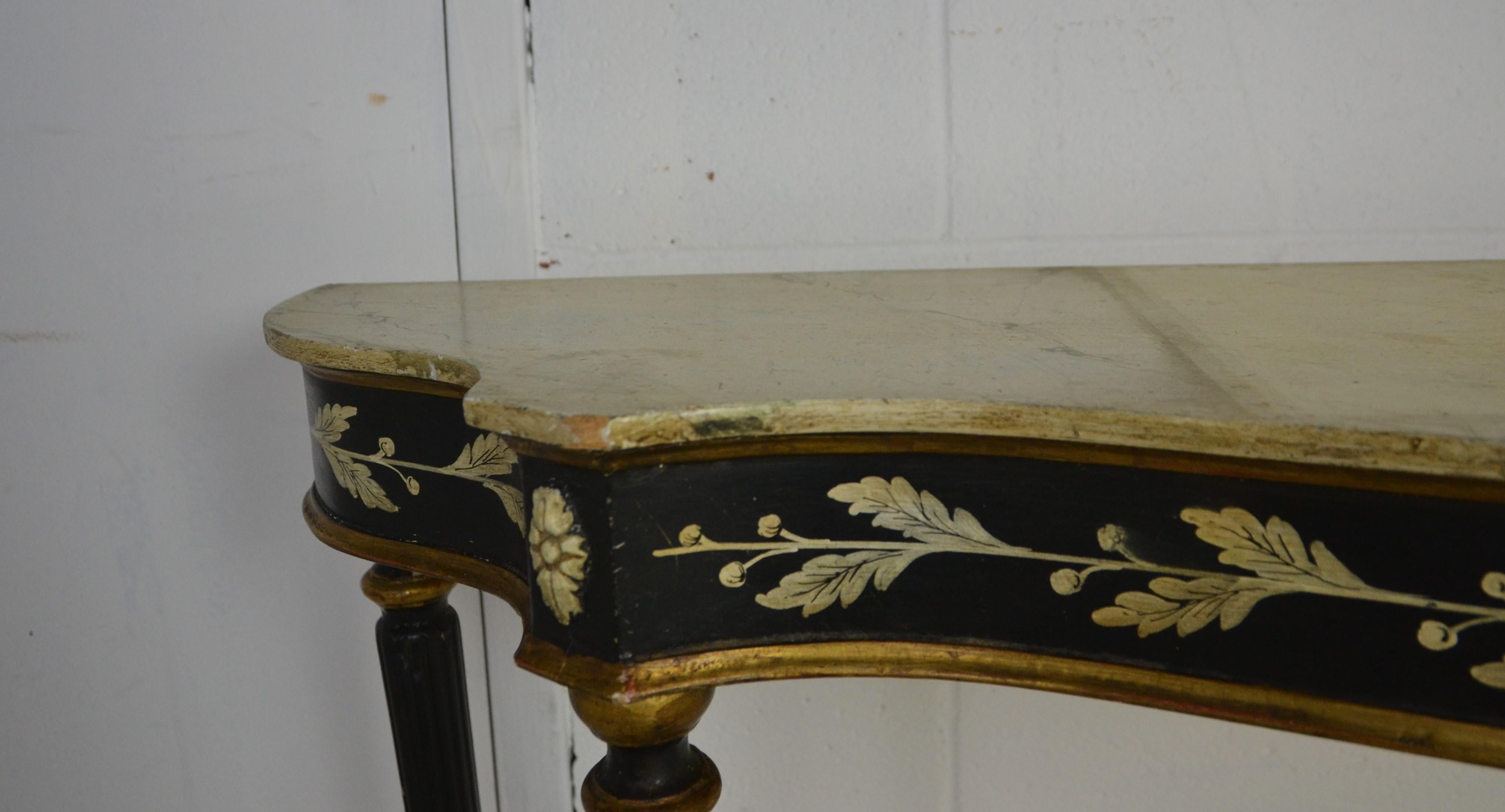 A Louis XVI style console table. Reeded legs. Hand painted black finish with a white painted leaf decoration. Gilded edge to the front. Faux marble top.