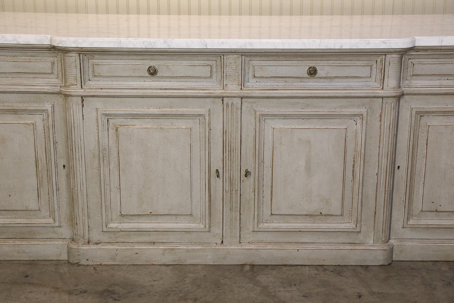 Very Large Louis XVI-style walnut credenza has been painted a grey wash and topped with a shaped white marble.

Credenza features four paneled drawers and cabinet doors for optimal storage.

Front ends of cabinet are simple columns with the marble