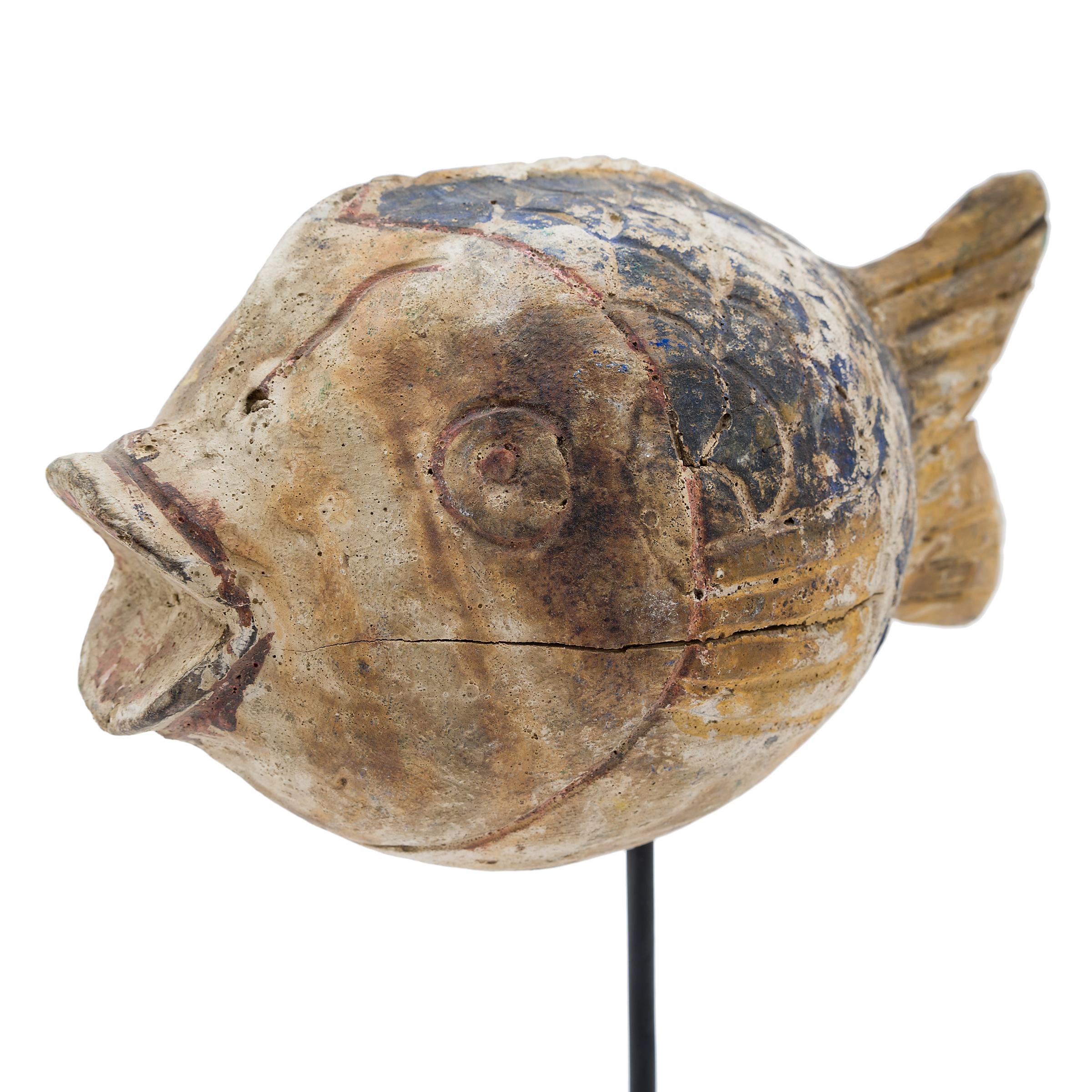 Hand-carved from reclaimed wood, this rustic koi sculpture recreates early 20th-century Chinese folk art designs. The fish is carved with a squat, rounded body and finished with blue and yellow pigments. Common motifs in Chinese art, fish are