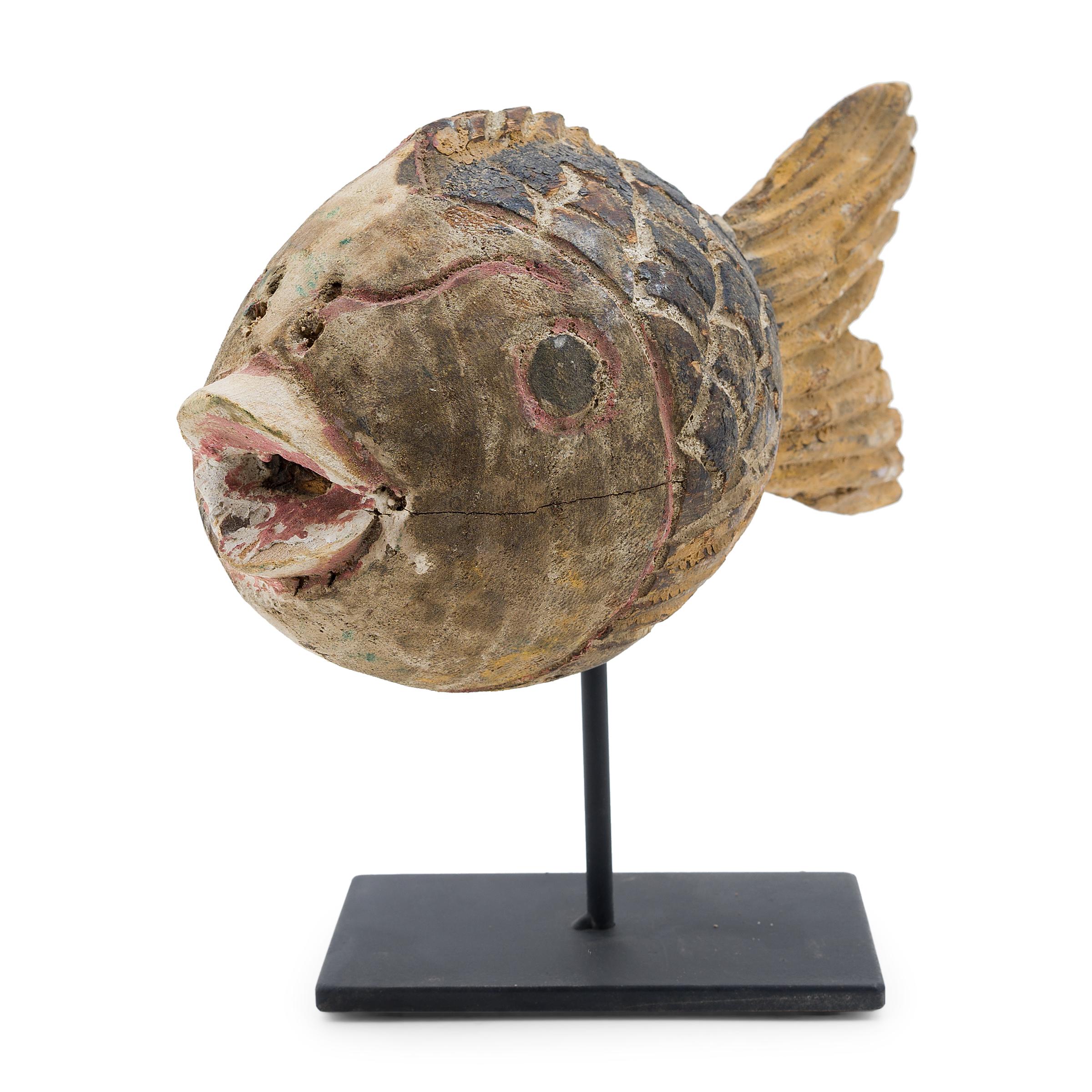 Hand-carved from reclaimed wood, this rustic koi sculpture recreates early 20th-century Chinese folk art designs. The fish is carved with a squat, rounded body and finished with blue and yellow pigments. Common motifs in Chinese art, fish are