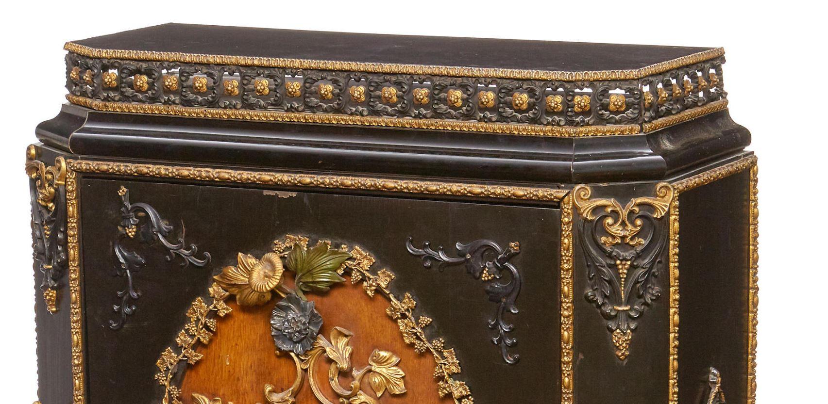 One-of-a-kind and spectacular continental gilt and painted metal mounted ebonized side cabinet, 19th century.

The rectangular ebonized top with a parcel gilt floral motif filigree border is over a large door heavily decorated with intricate