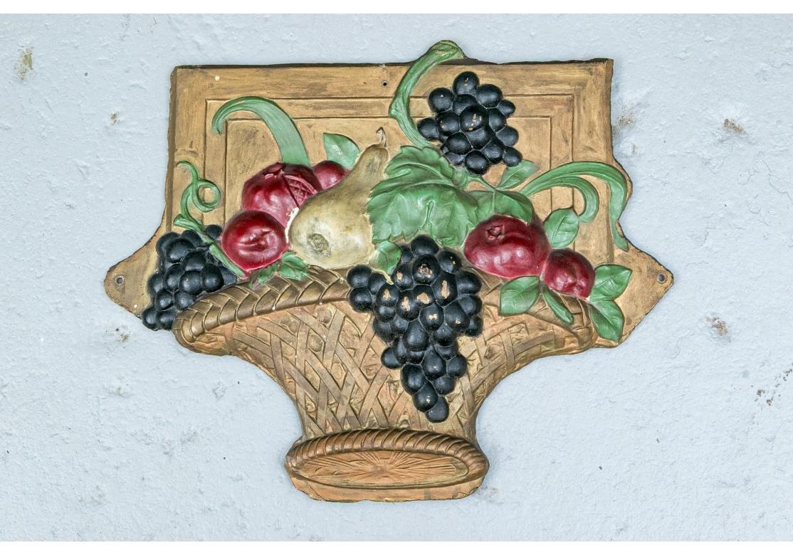 A colorful and decorative cast metal plaque depicting a woven basket overflowing with Grapes, Pears, Apples and green leafy foliage. With holes for wall mounting. 

Dimensions:  23