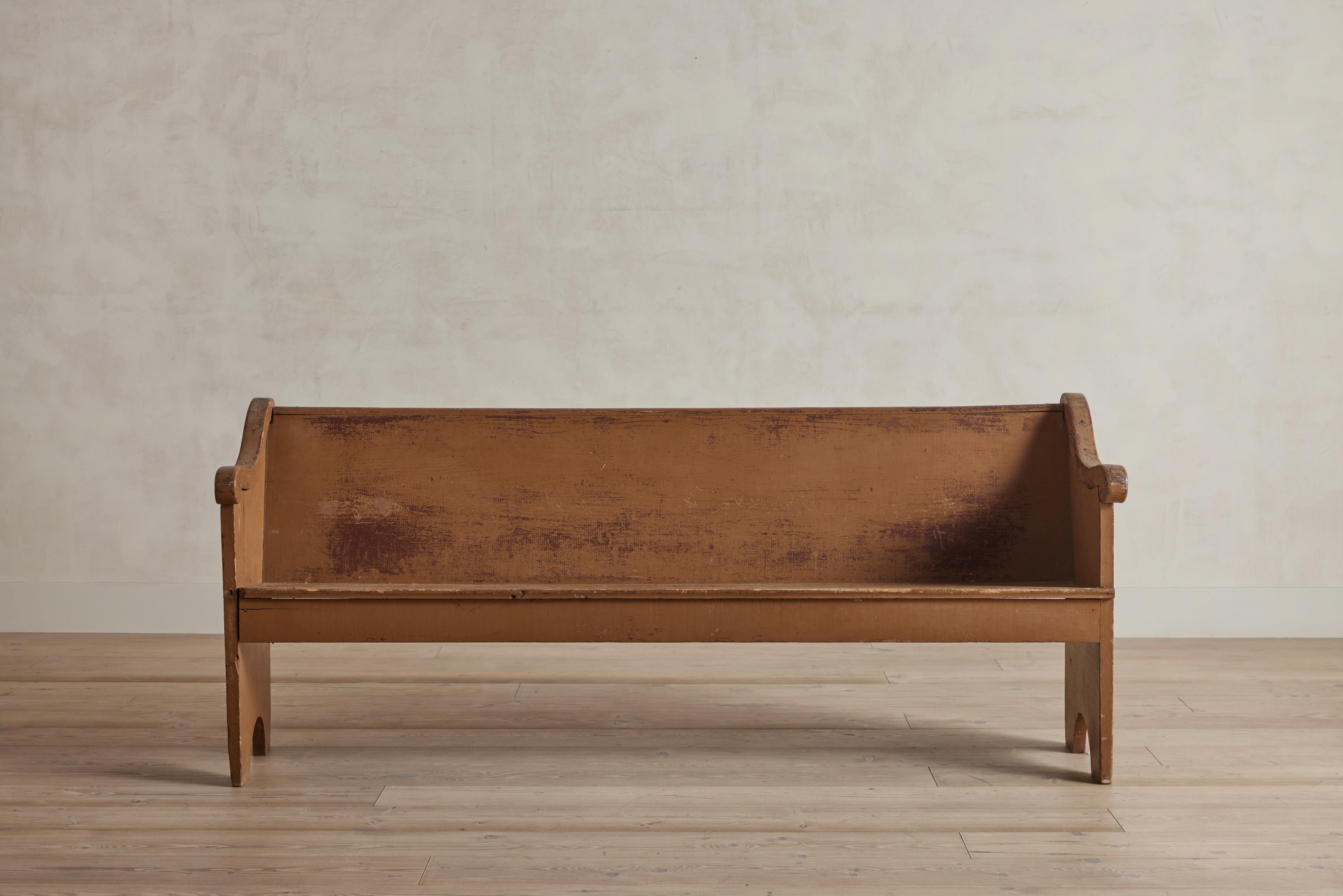 Early American wood bench painted in a rich mustard hue. This bench was most likely used as a church pew. There is visible wear on wood and painted finish that is consistent with age and use. United States, circa 1850.