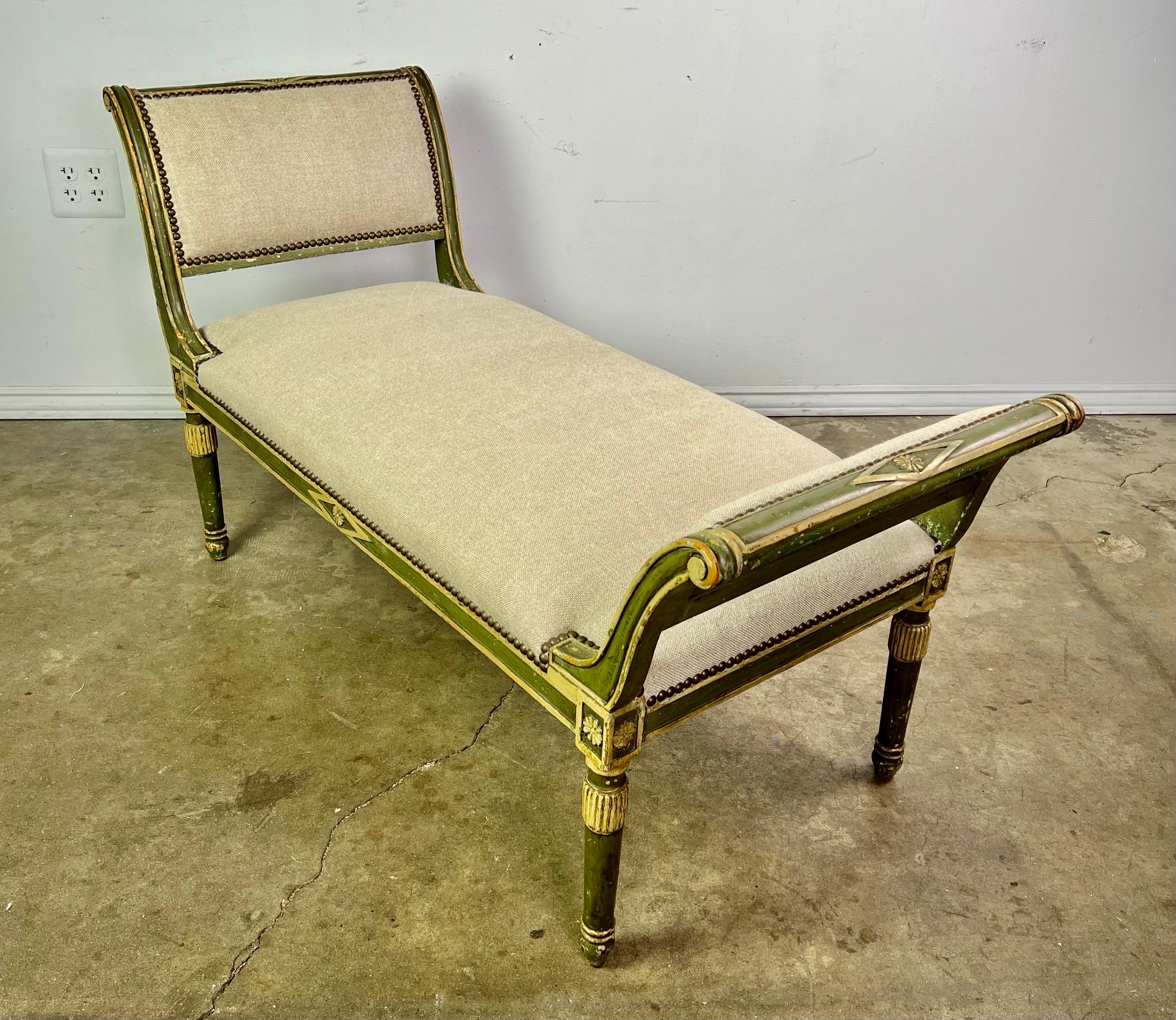 Italian painted neoclassical style bench in a green coloration with gold details throughout. The bench is newly upholstered in a washed Belgium linen with brass nailhead trim detail.