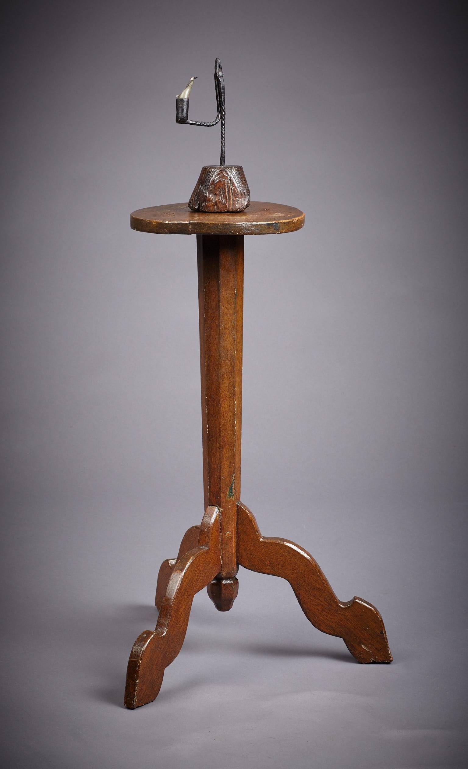 Early 18th century, Queen Anne period, painted oak candle-stand on triform base.

With small circular top above a tapered octagonal chamfered stem, terminating on original octagonal drop, supported on three shaped and splayed legs. Having 19th