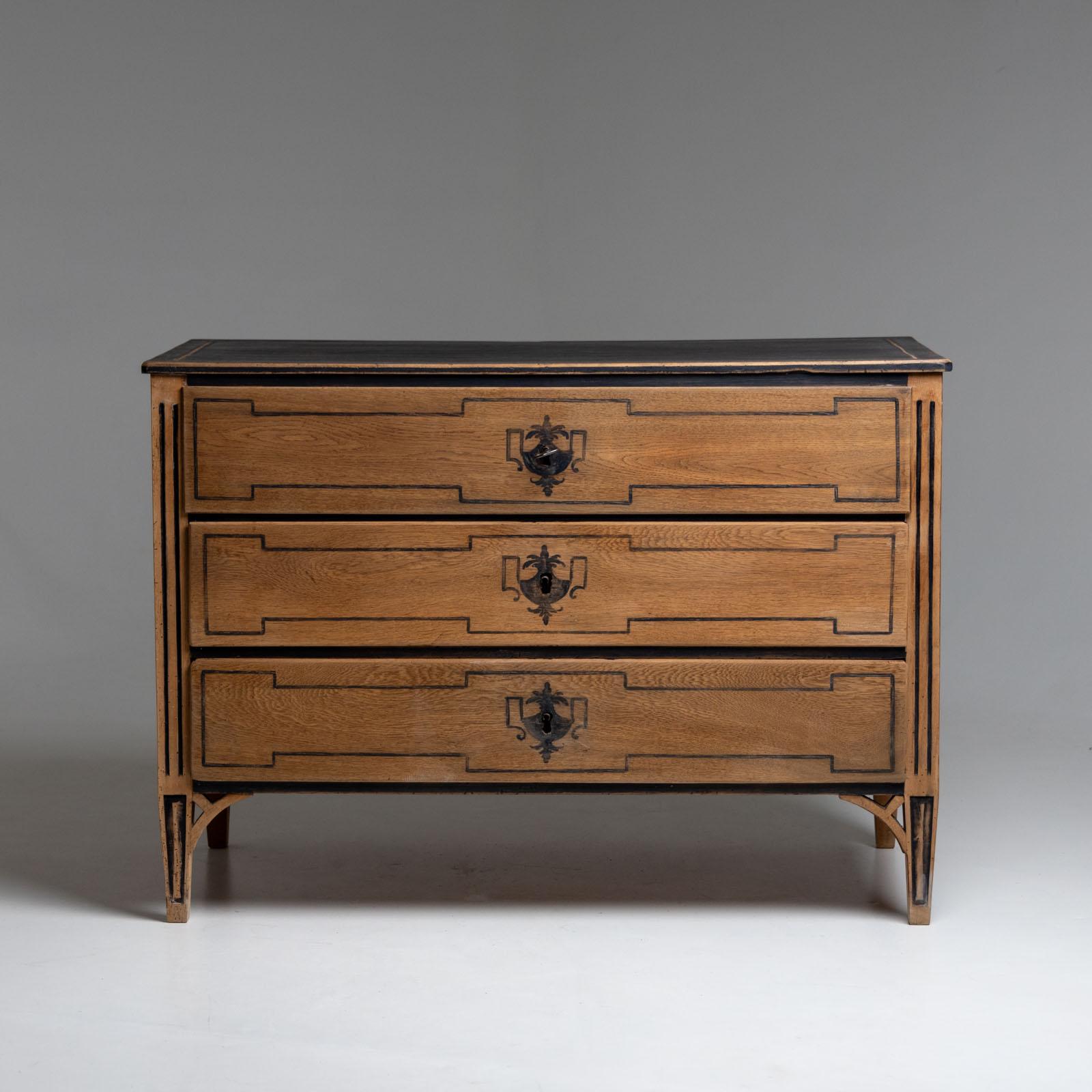 Large chest of drawers made of solid oak with black urn decoration and framing paintings on the front. The top panel is painted black and the carved fluting on the pilaster strips is also set off in dark. The chest of drawers has three drawers and