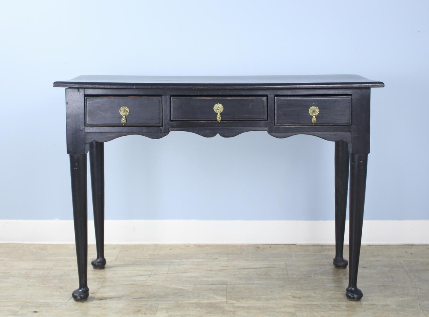 An elegant small serving table or hall table, newly painted in muted black with small amounts of faux distress. Brass tear drop escutcheons are period appropriate. Useful length and depth.